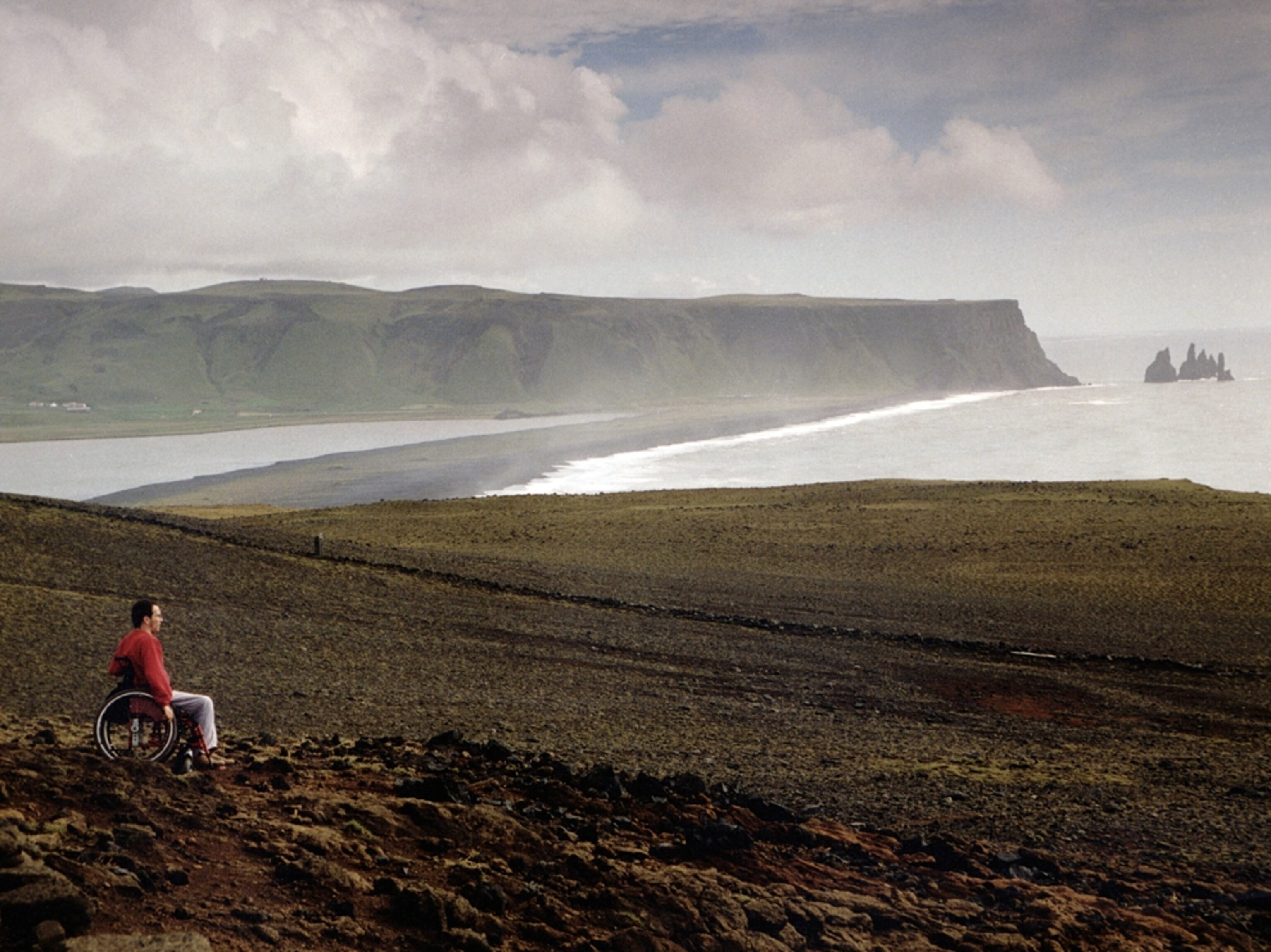 Man in wheelchair looks at ocean Iceland
