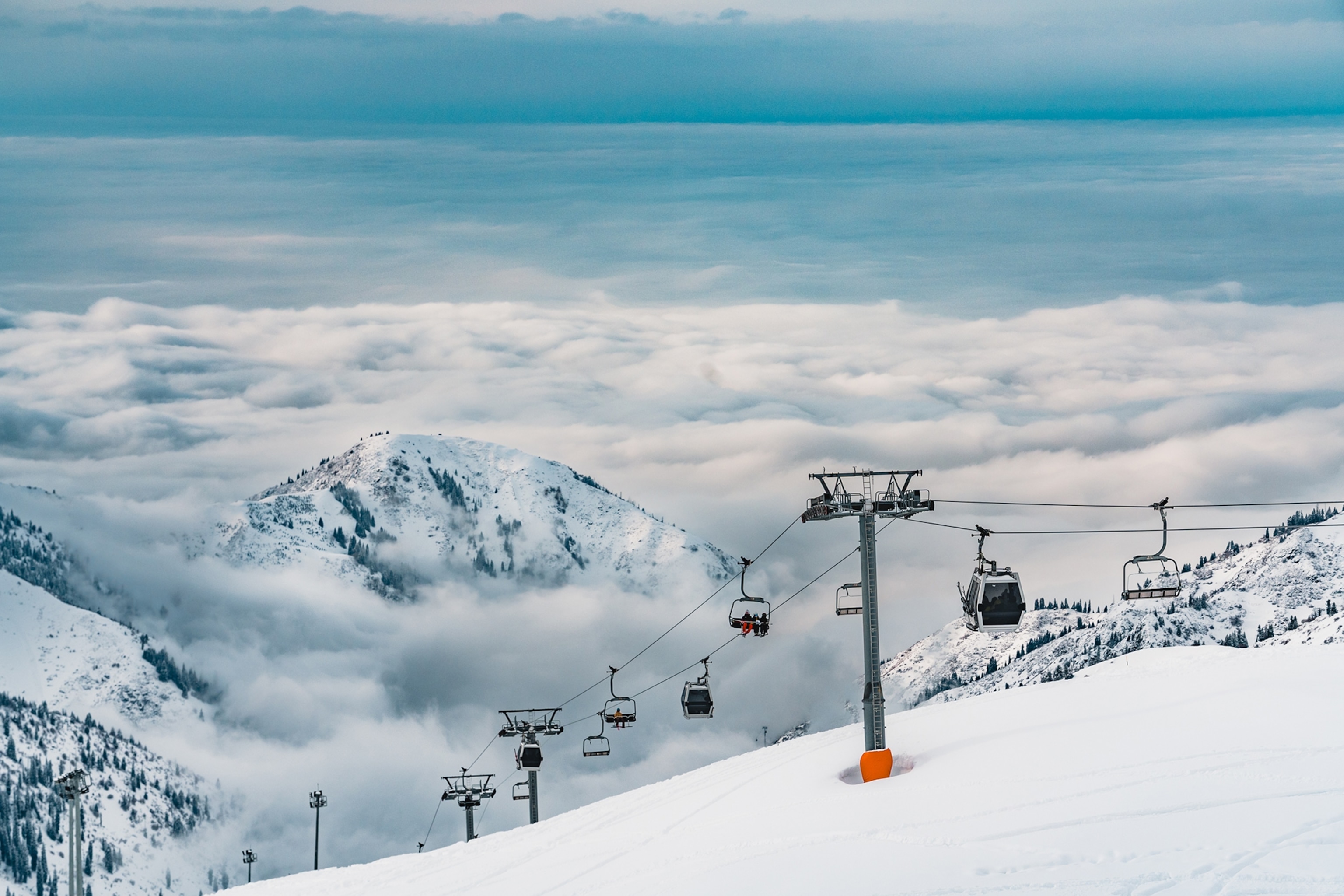 A ski lift carrying gondolas up a snowy mountain.