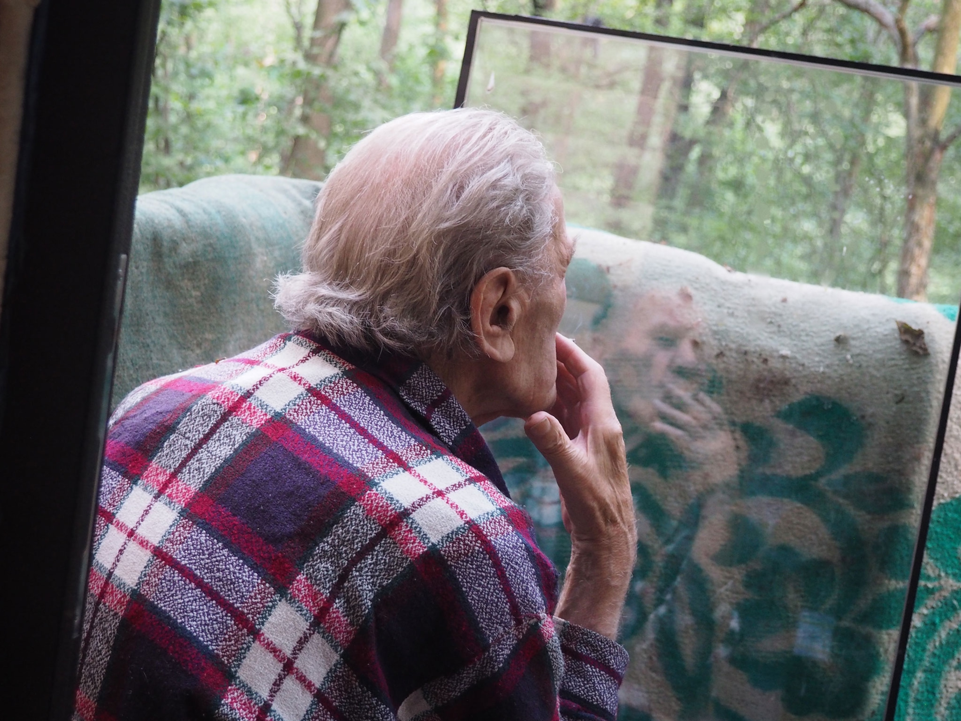 An elderly man smokes a cigarette on the doorstep of his lodging in Ukraine