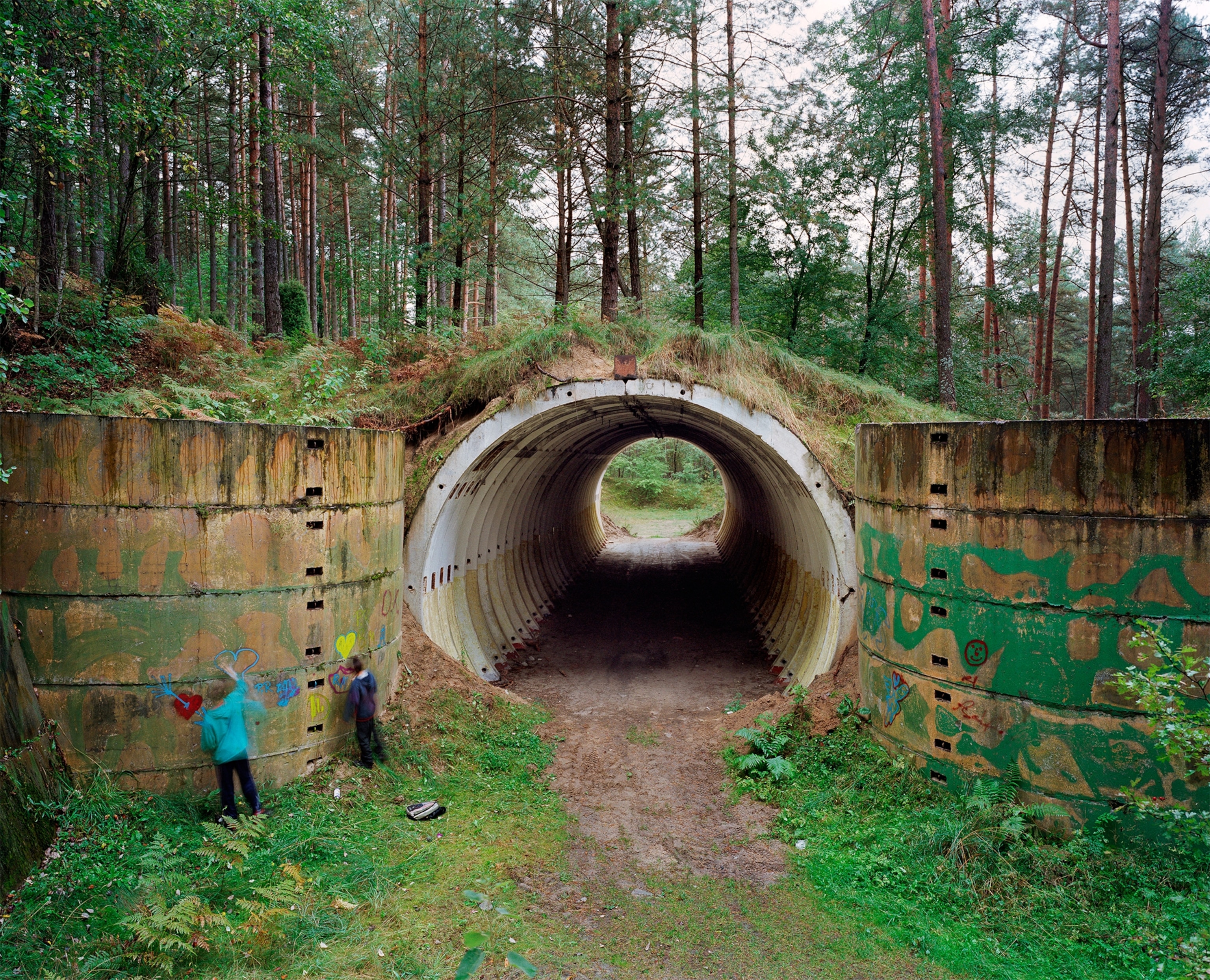 children painting graffiti on the concrete walls of an abandoned missile silo used by the Russian Army during the Cold War.