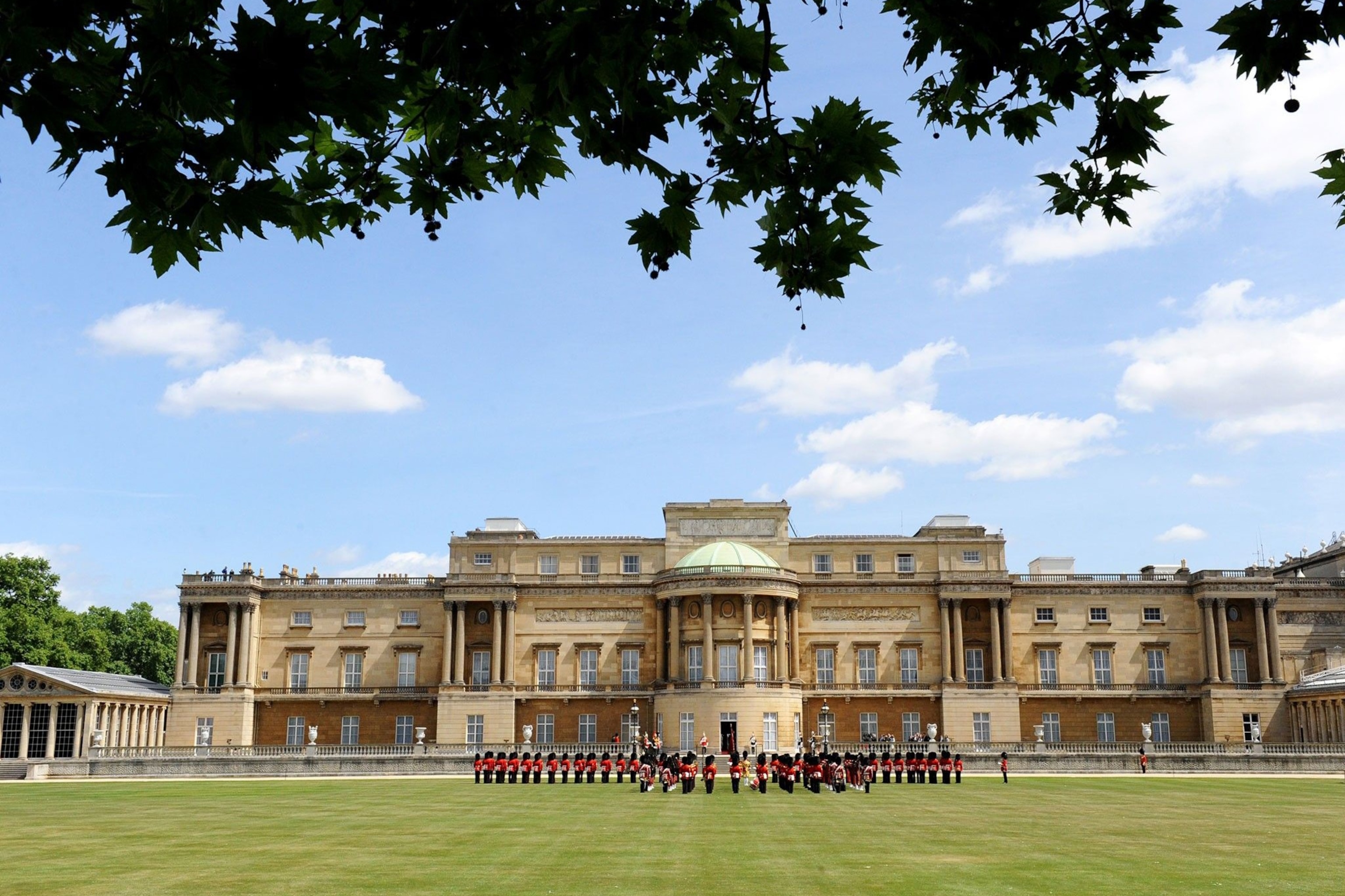 Front view of Buckingham Palace, with guards standing in formation in front.