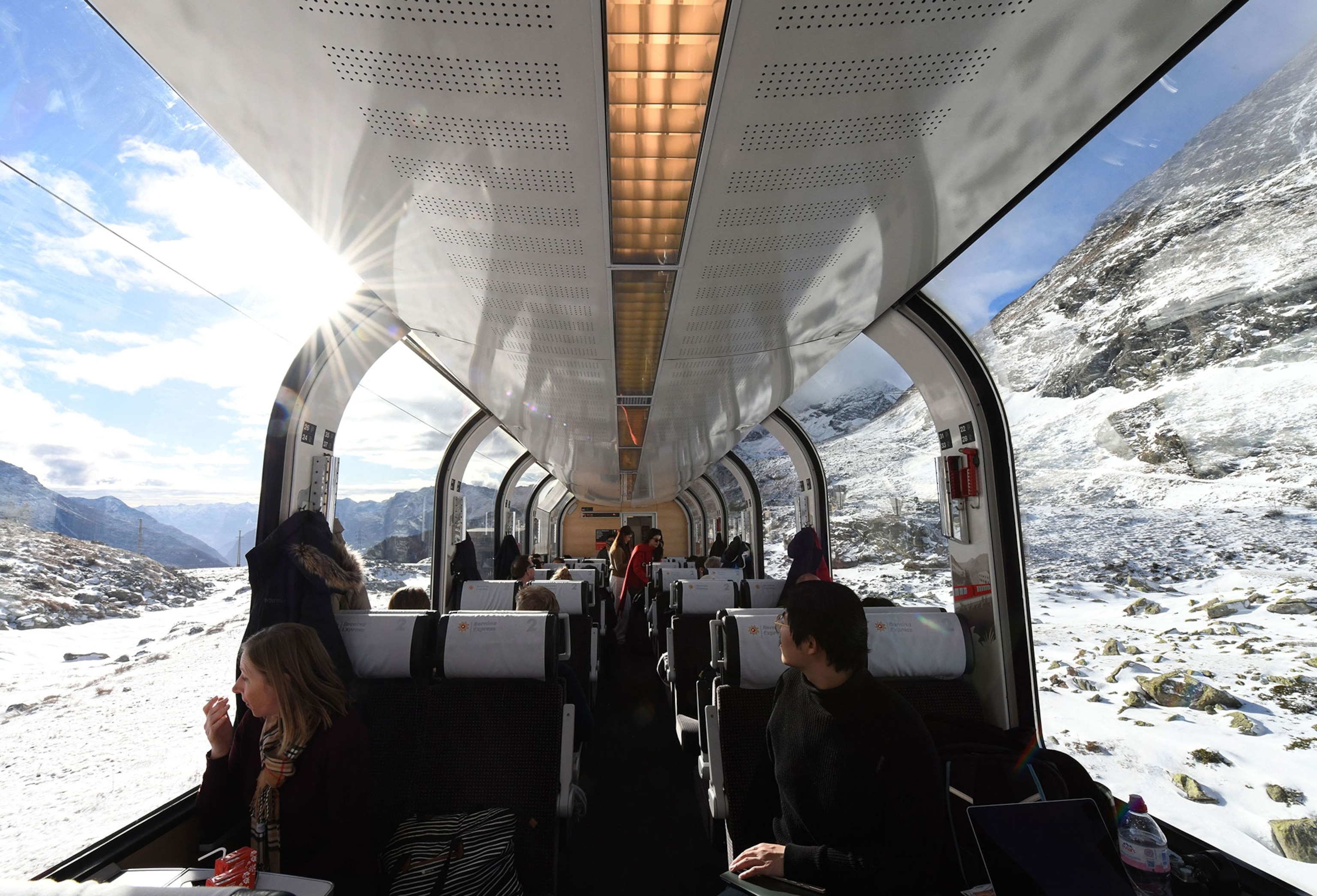 Tourists aboard the panoramic train enjoy the scenery along the Albula-Bernina railway in Switzerland