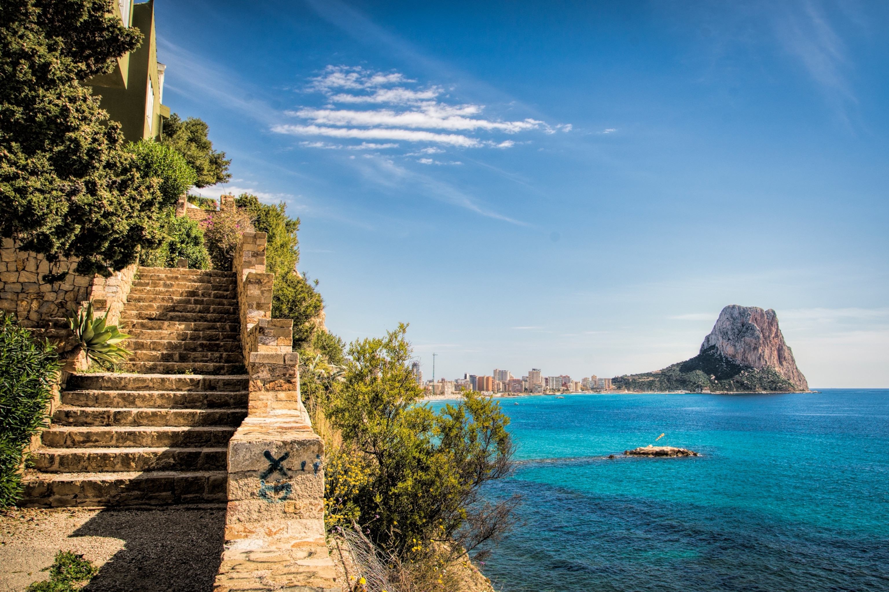 View of the Rock of Calpe in the Mediterranean Sea off the coast of Spain on the Costa Blanca Coast along with a stone staircase ascending a cliff.