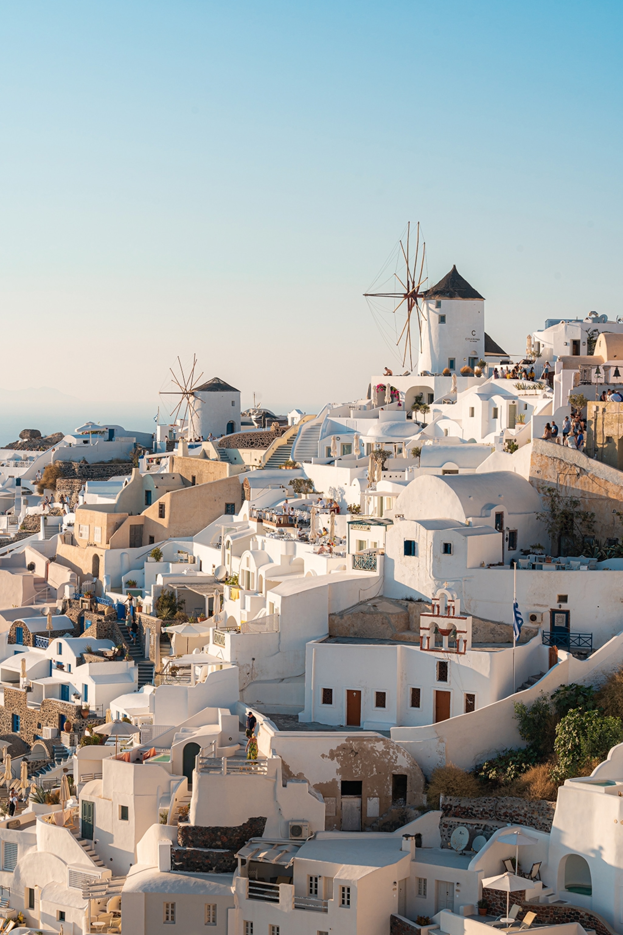 A view of a hill with Cycladic houses and a church at the top.