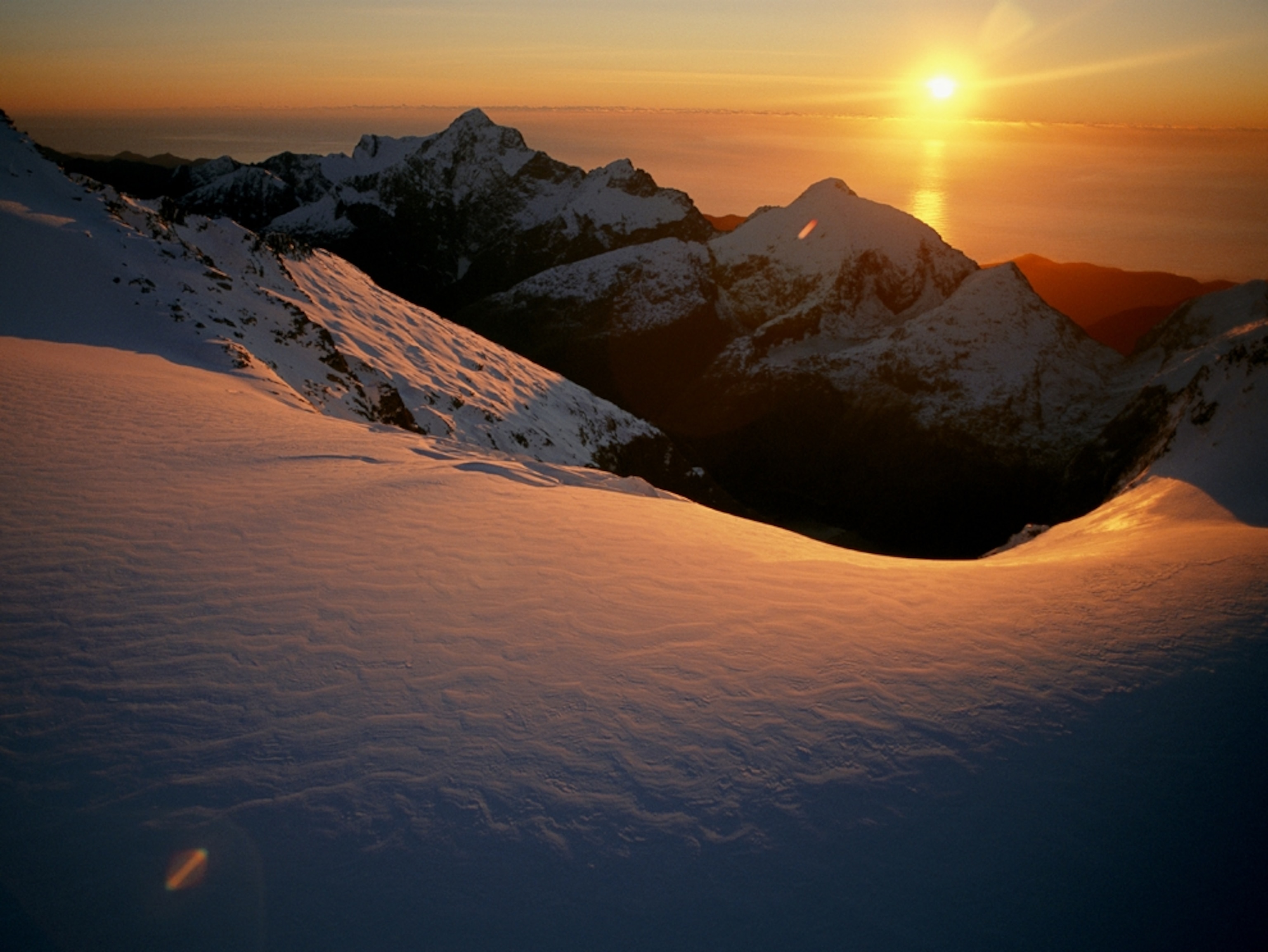 a sunset glow over a glacier in Fiordland National Park. The Tasman Sea