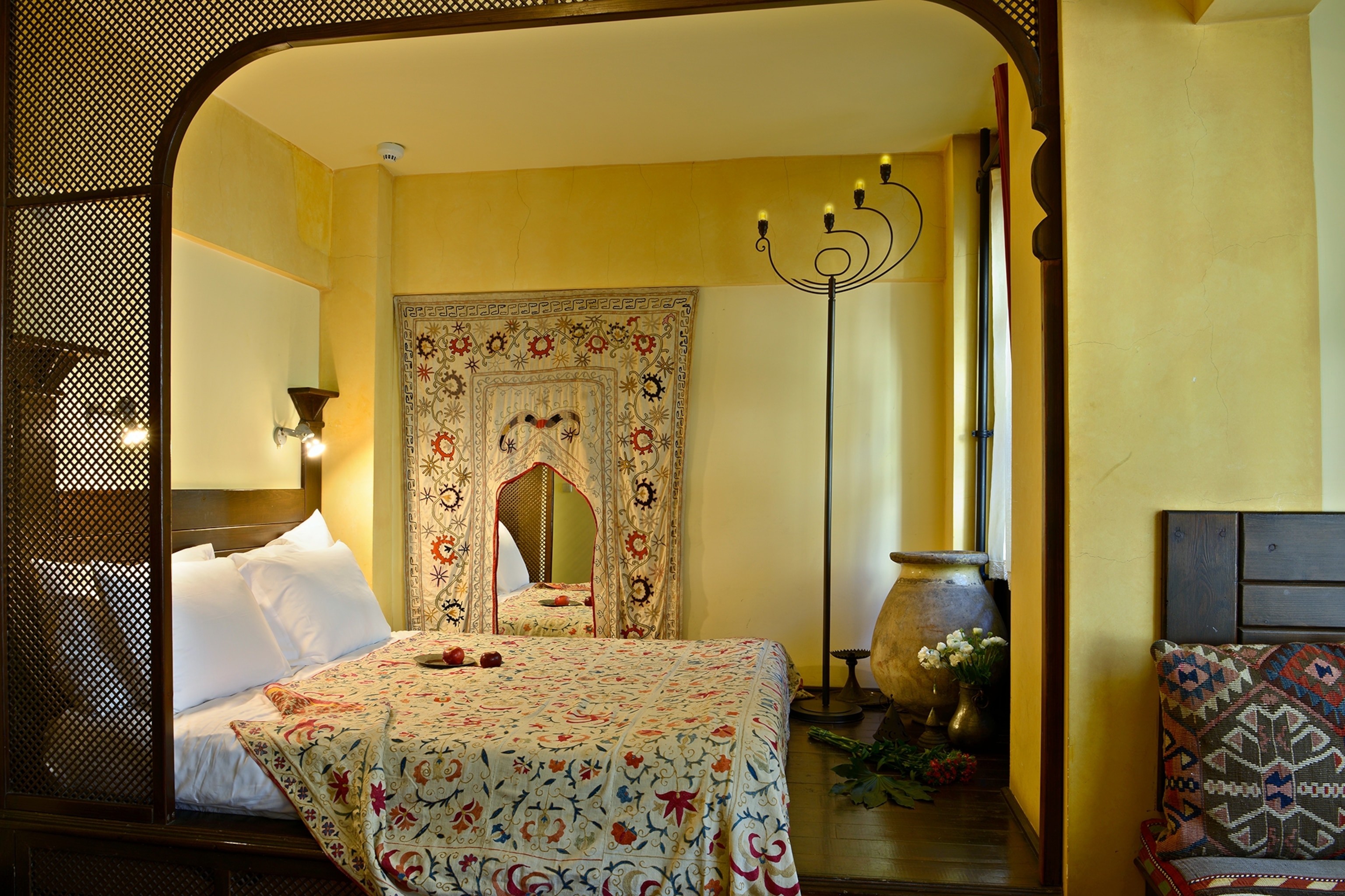 A quirky and traditional Ottoman with a tapestry hung on the wall and a decorative, arched doorway.