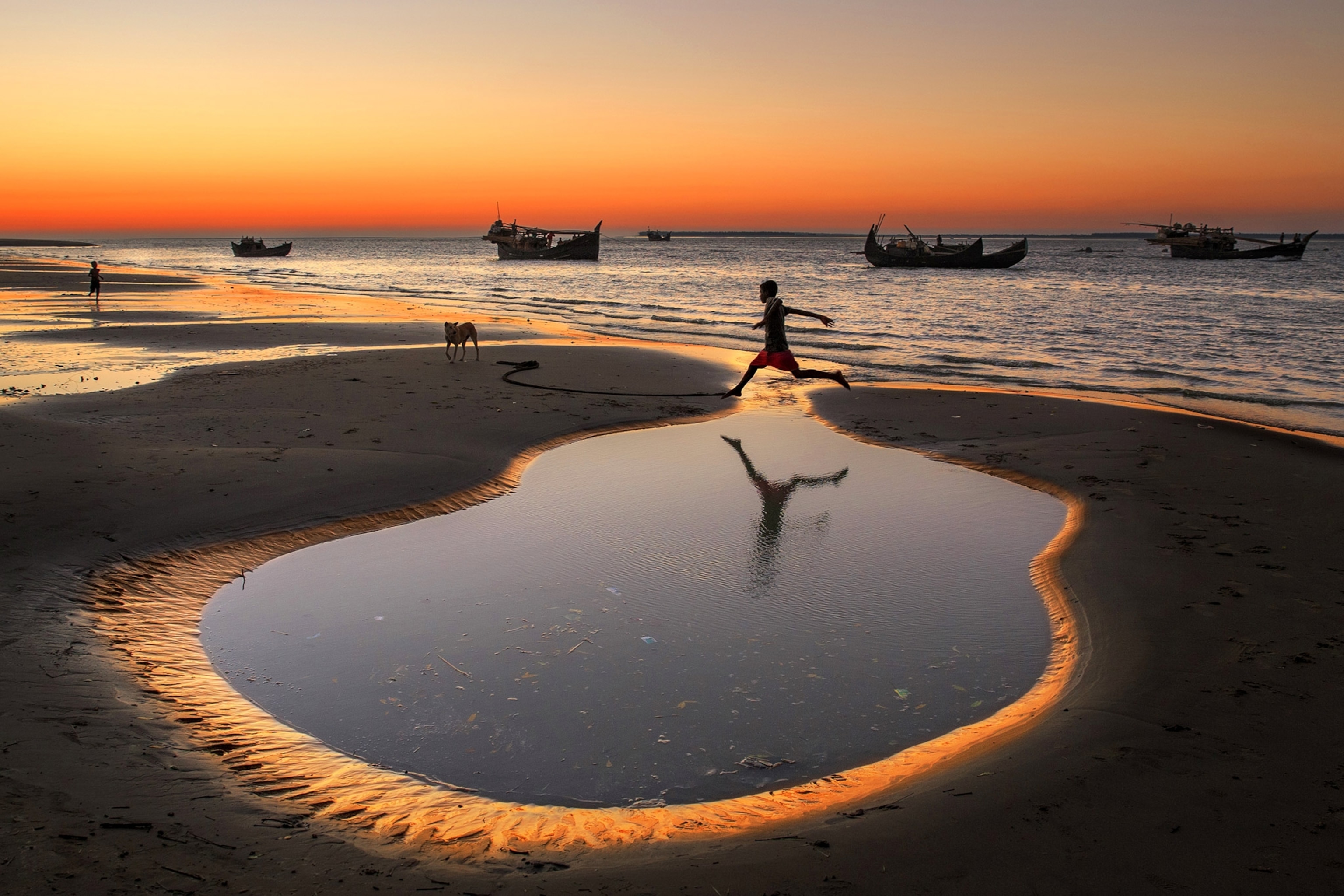 a boy jumping over a puddle at Cox's Bazar, Bangladesh