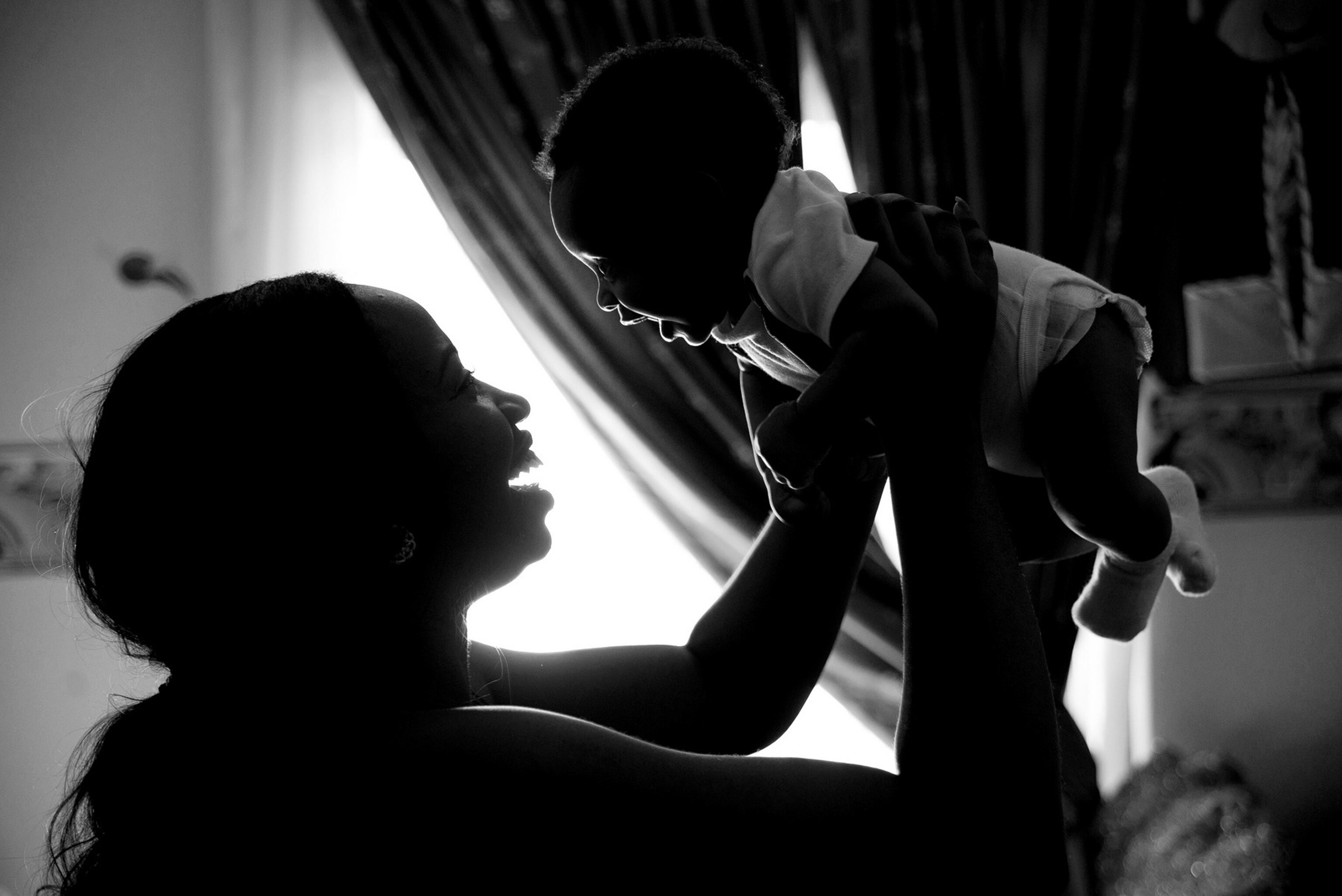 a smiling mother holding her smiling baby