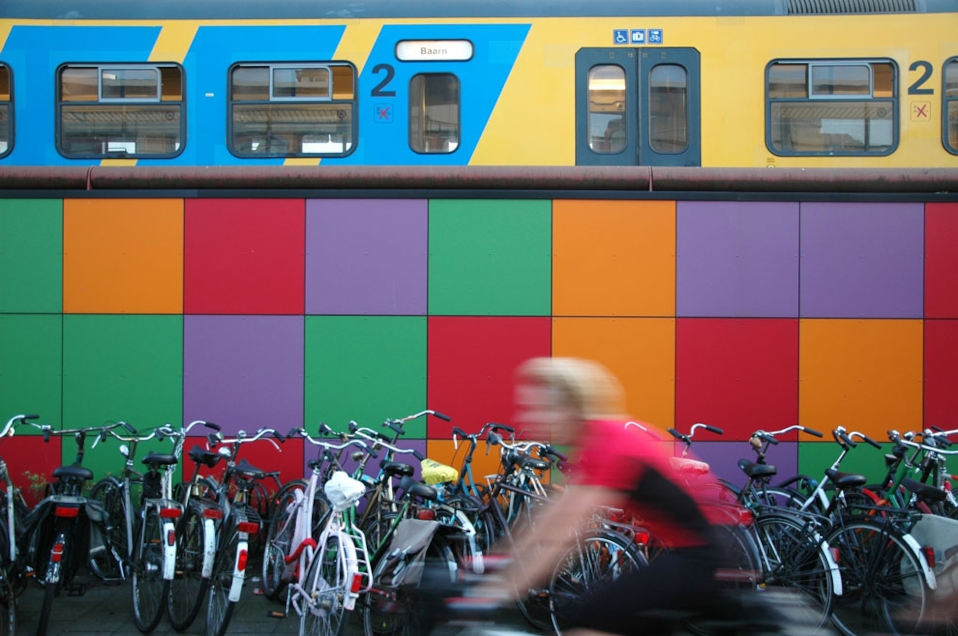 A biker passes a colorful train station wall in Utrecht, Netherlands