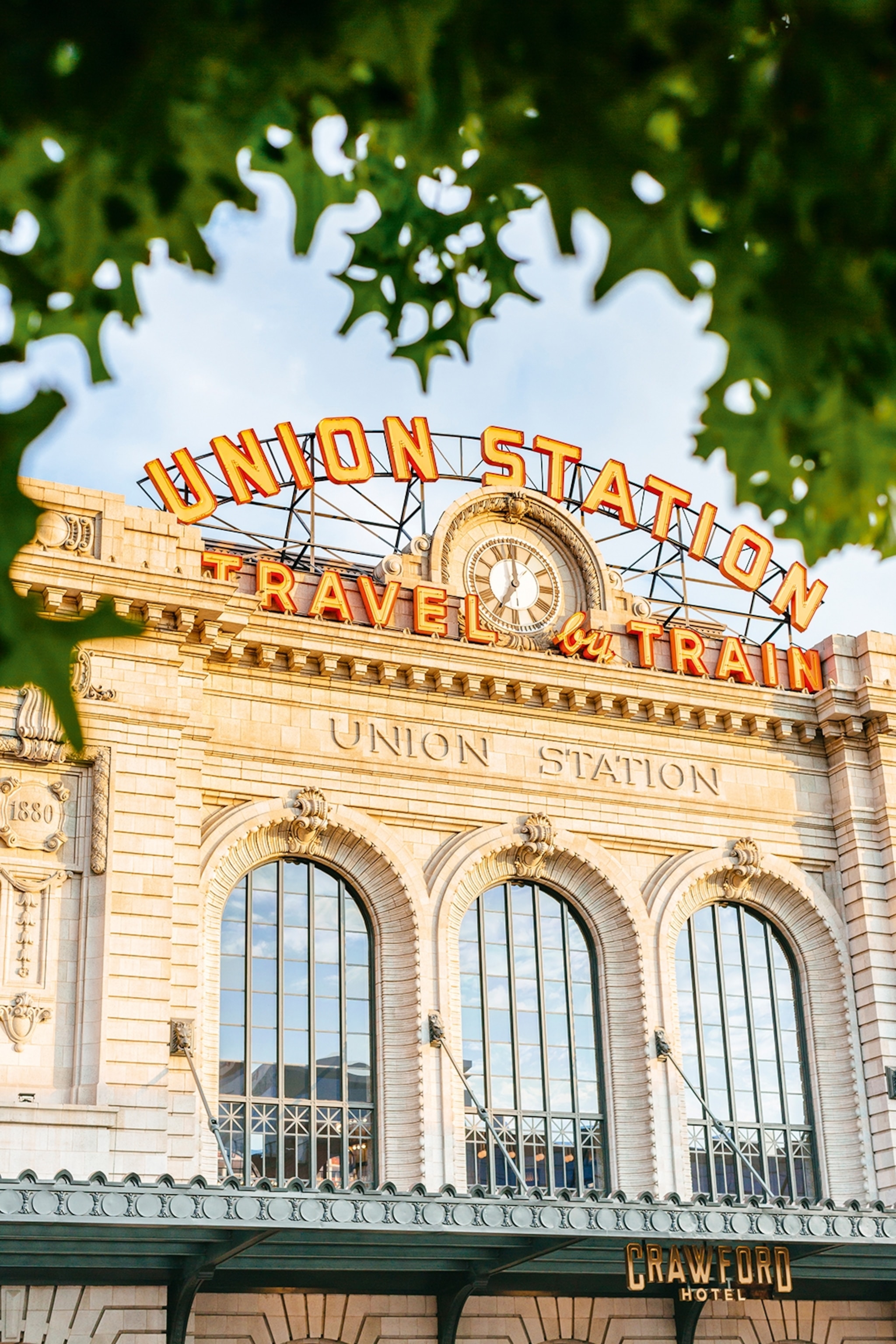 A grand train station with arched windows and curved neon lettering along the top of the building.