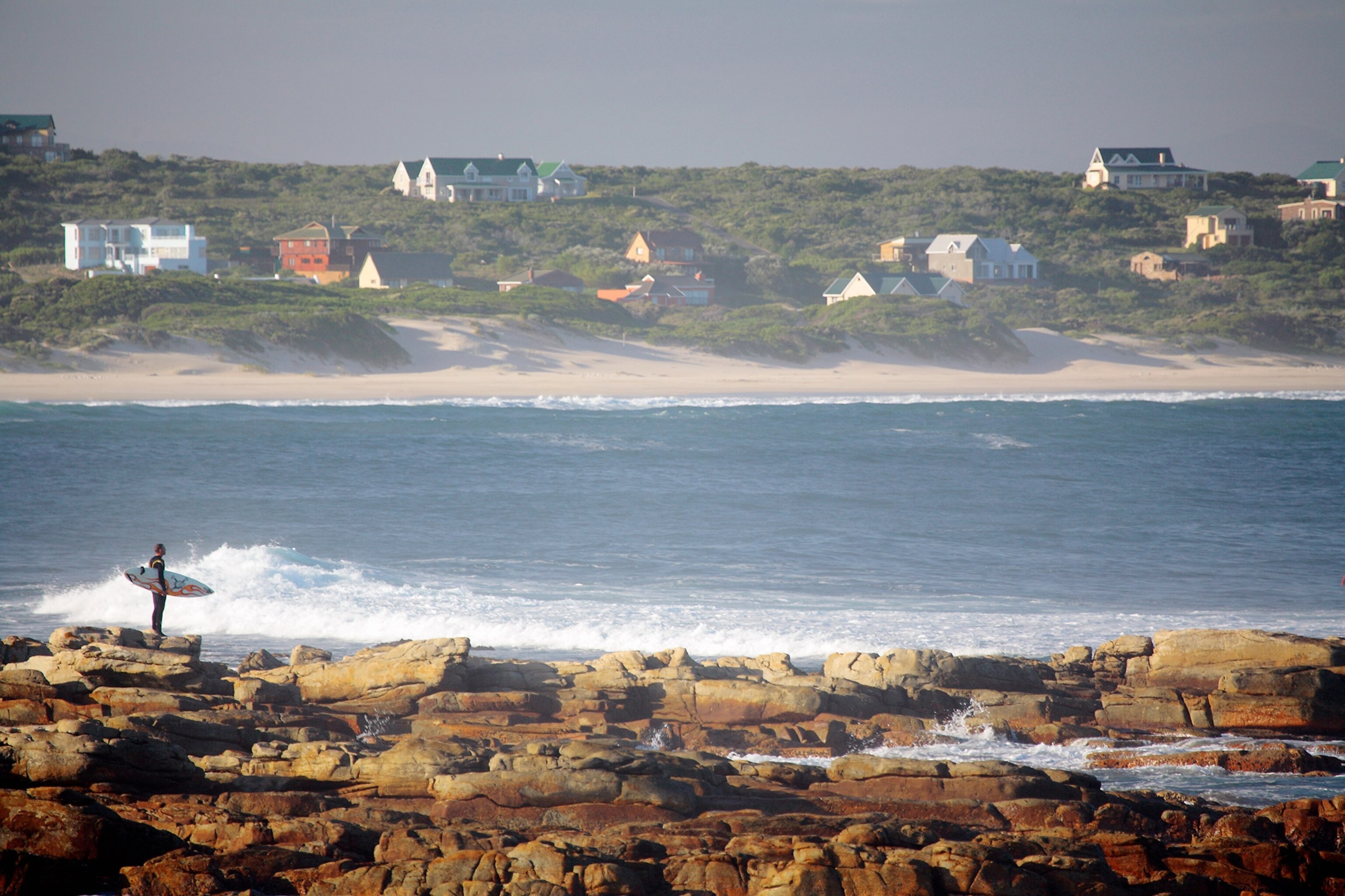 an early morning surfer on the shore of Cape St. Francis, Eastern Cape, South Africa