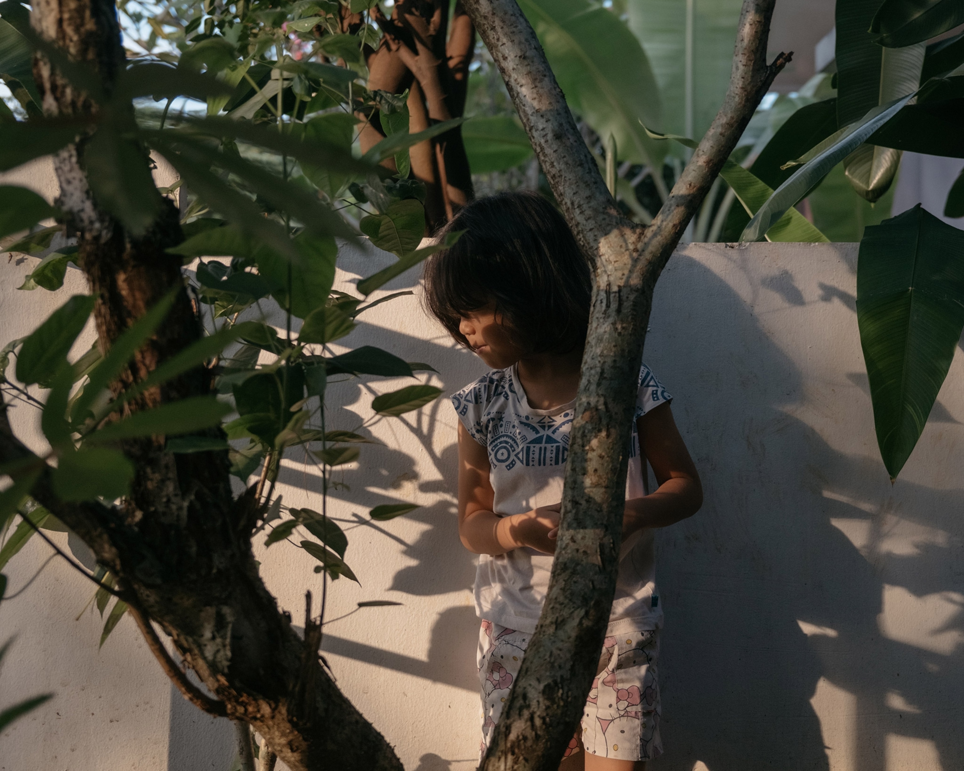 a little girl behind a tree