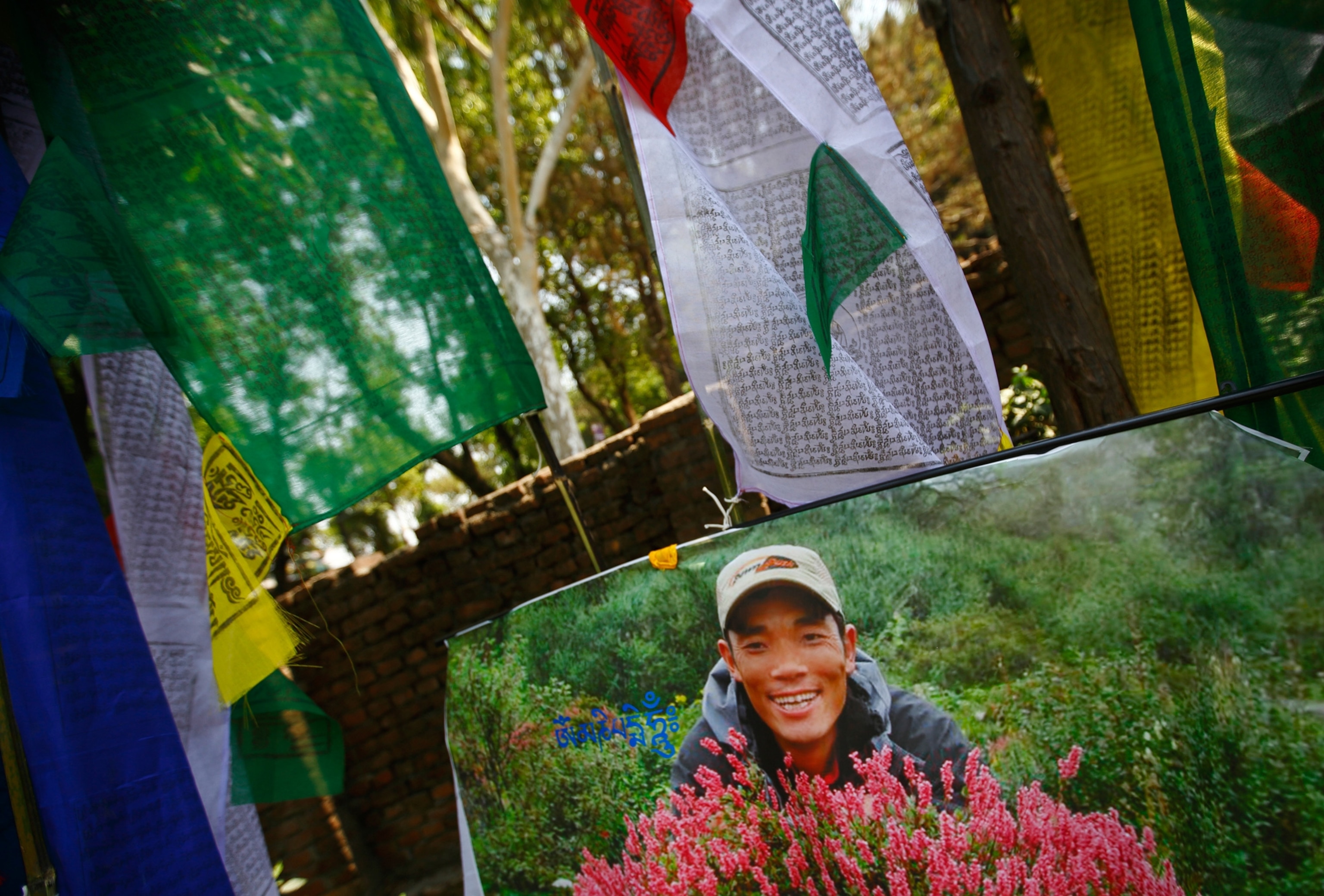 a portrait of Ankaji Sherpa and prayer flags.