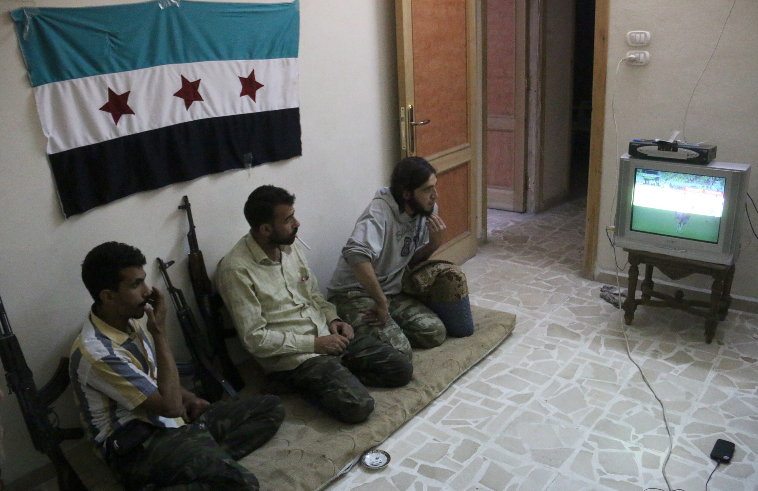 Rebel fighters watch on television the opening World Cup 2014 football match between Brazil and Croatia on June 12, 2014 in the northern Syrian city of Aleppo.