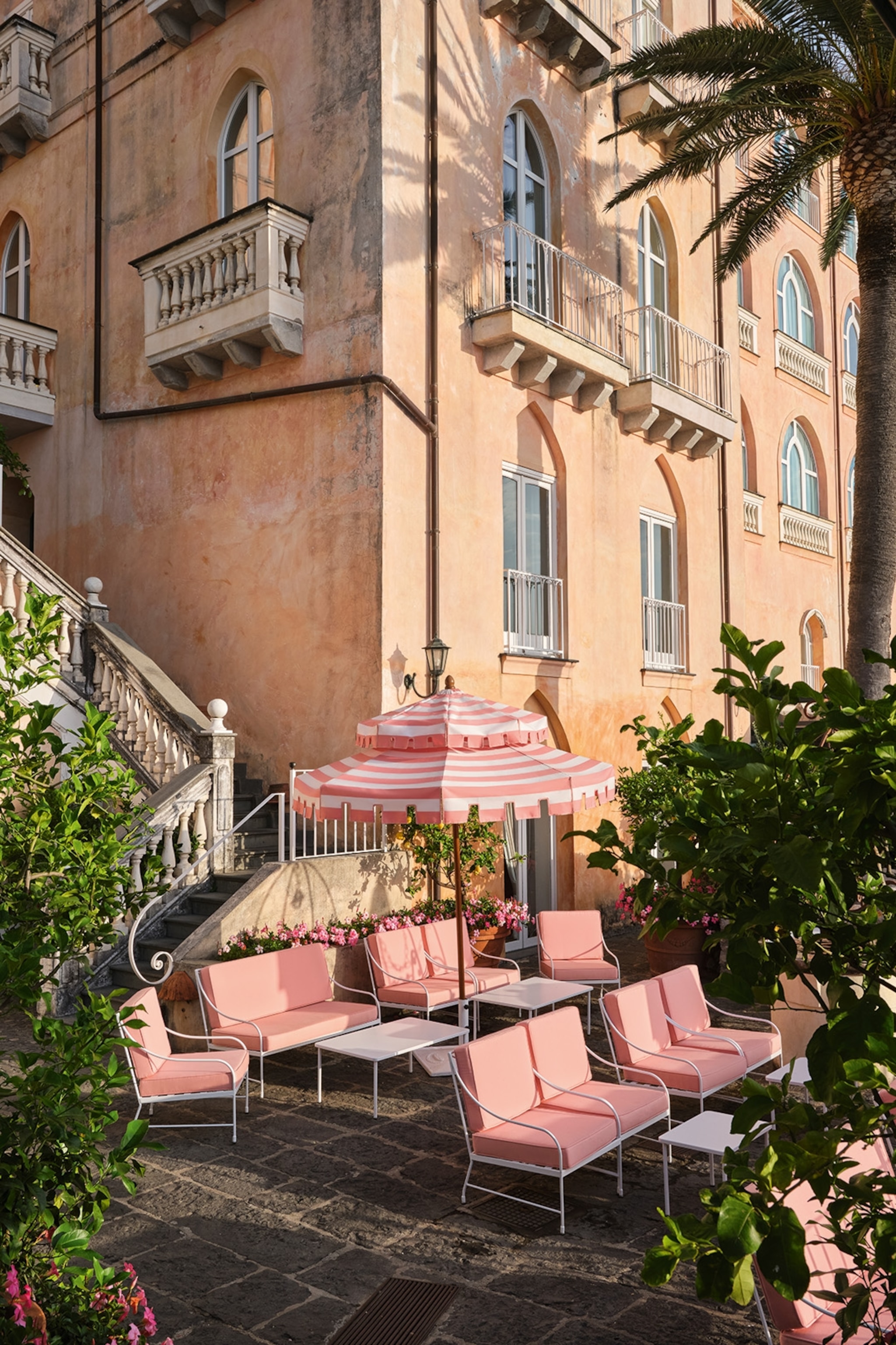 A light-pink Italian castle wall with pink deck chairs on its terrace.