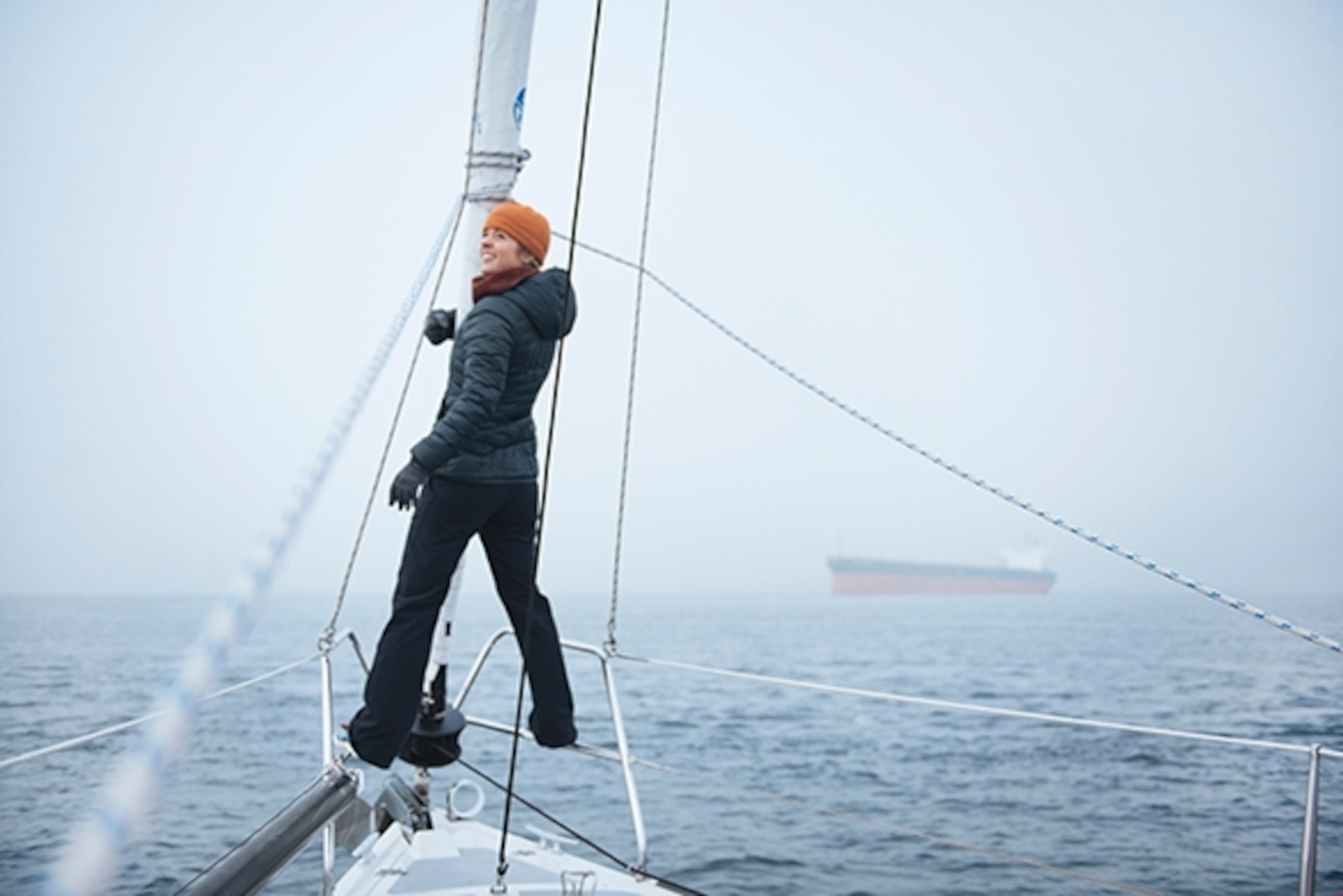 Maggie Tweedy stands on the bow of the sail boat en route to Blake Island, Washington; Photograph by Max Lowe
