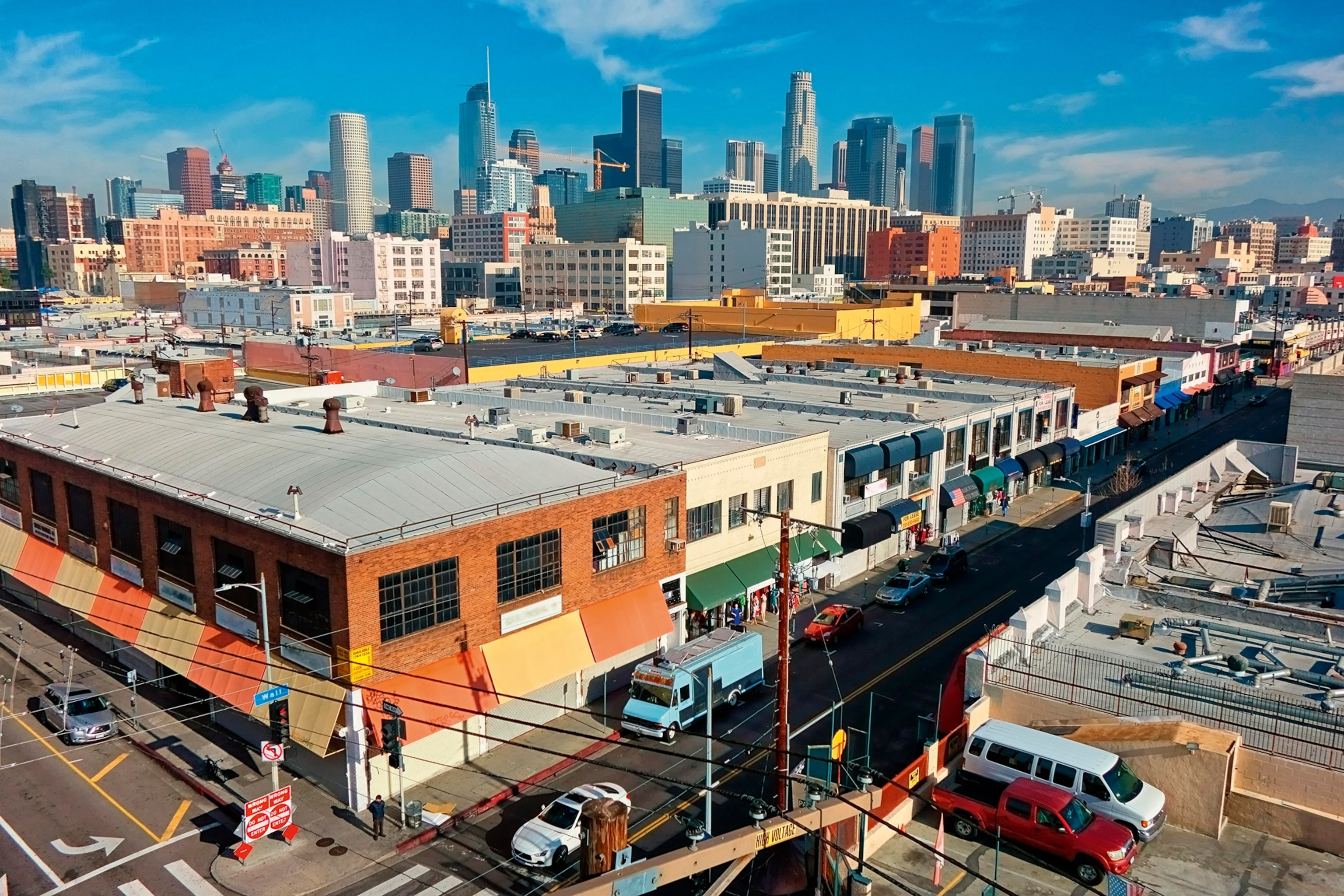 An aerial shot of LA's urban landscape with low factory buildings in the foreground and skyscrapers in the distance.