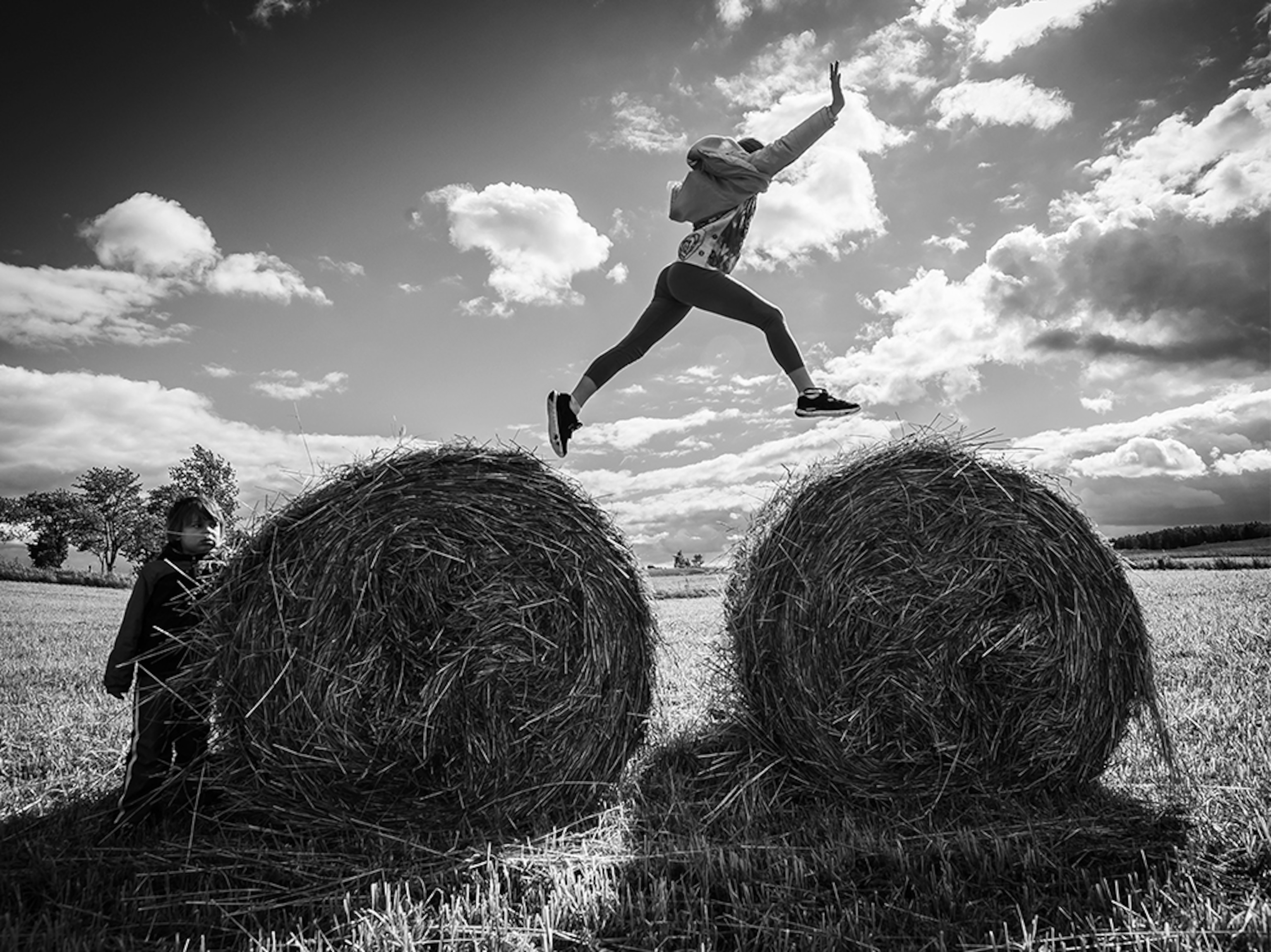 a girl jumping from one hay bale to another in the Masurian Lake District, Poland