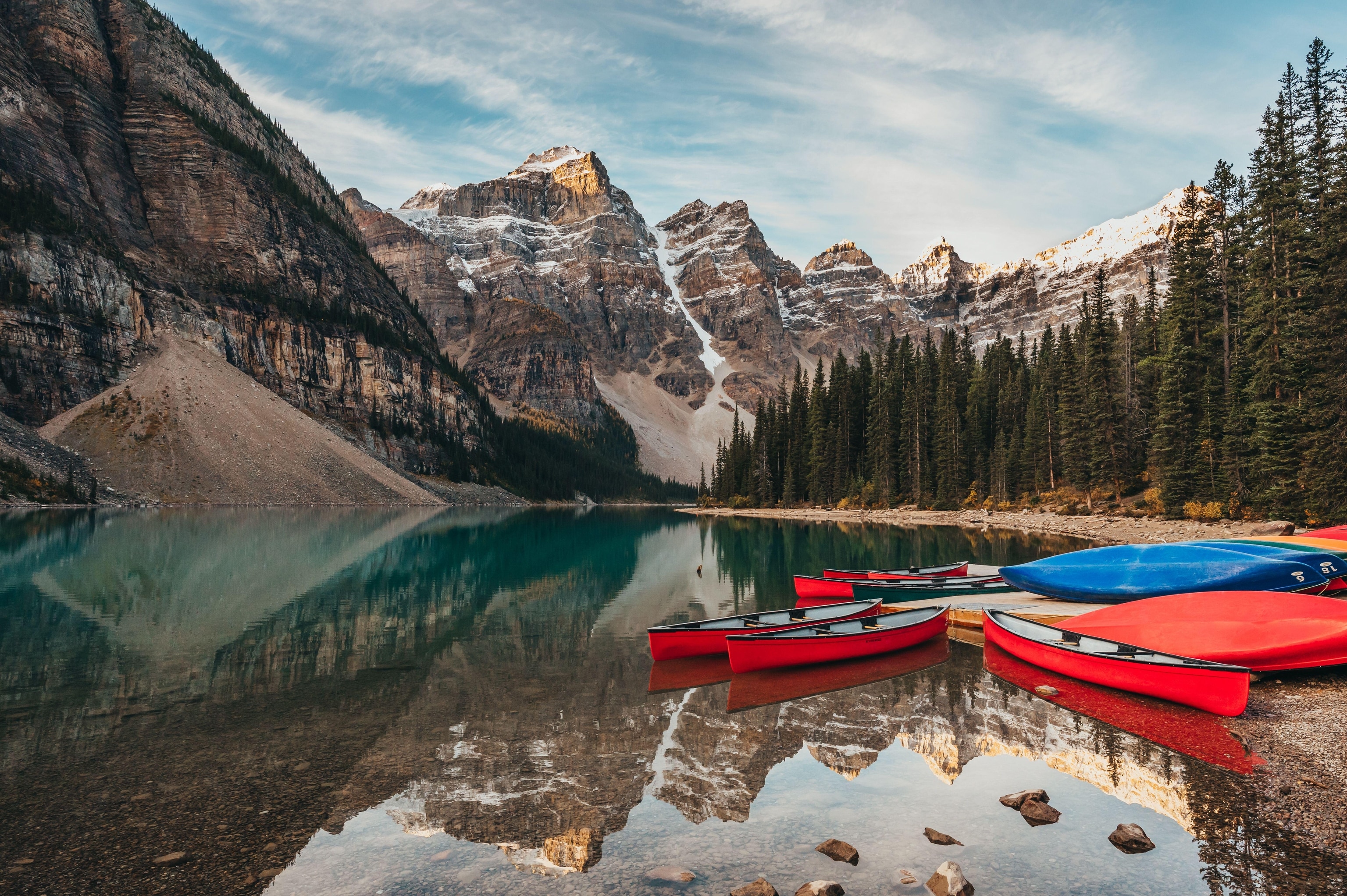 Red and blue canoes docked at a lake in the mountains.