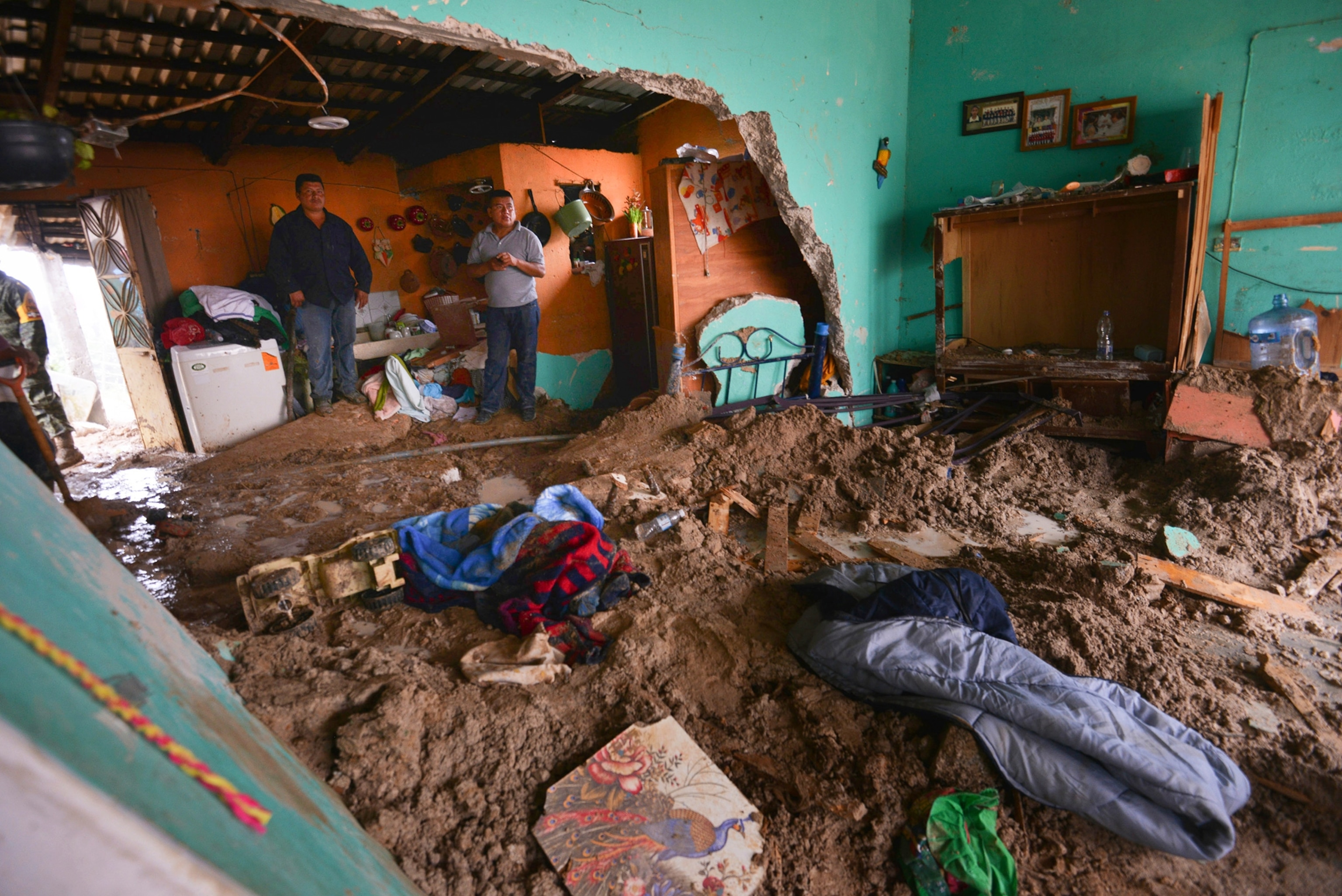 people standing in a house inundated with mud after a landslide in Altotonga, Veracruz, Mexico