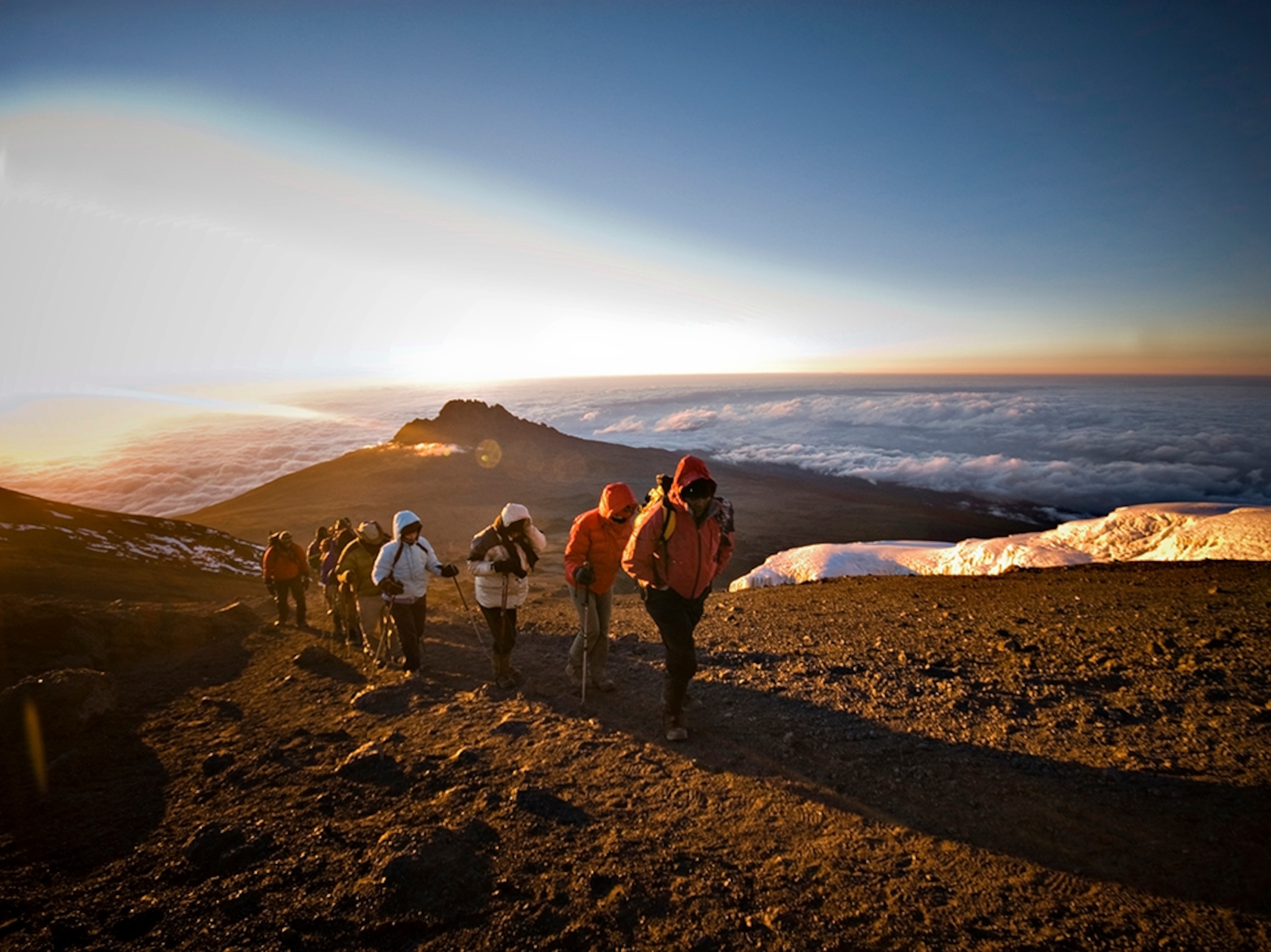 a team of hikers approaching the summit of Mt. Kilimanjaro at sunrise