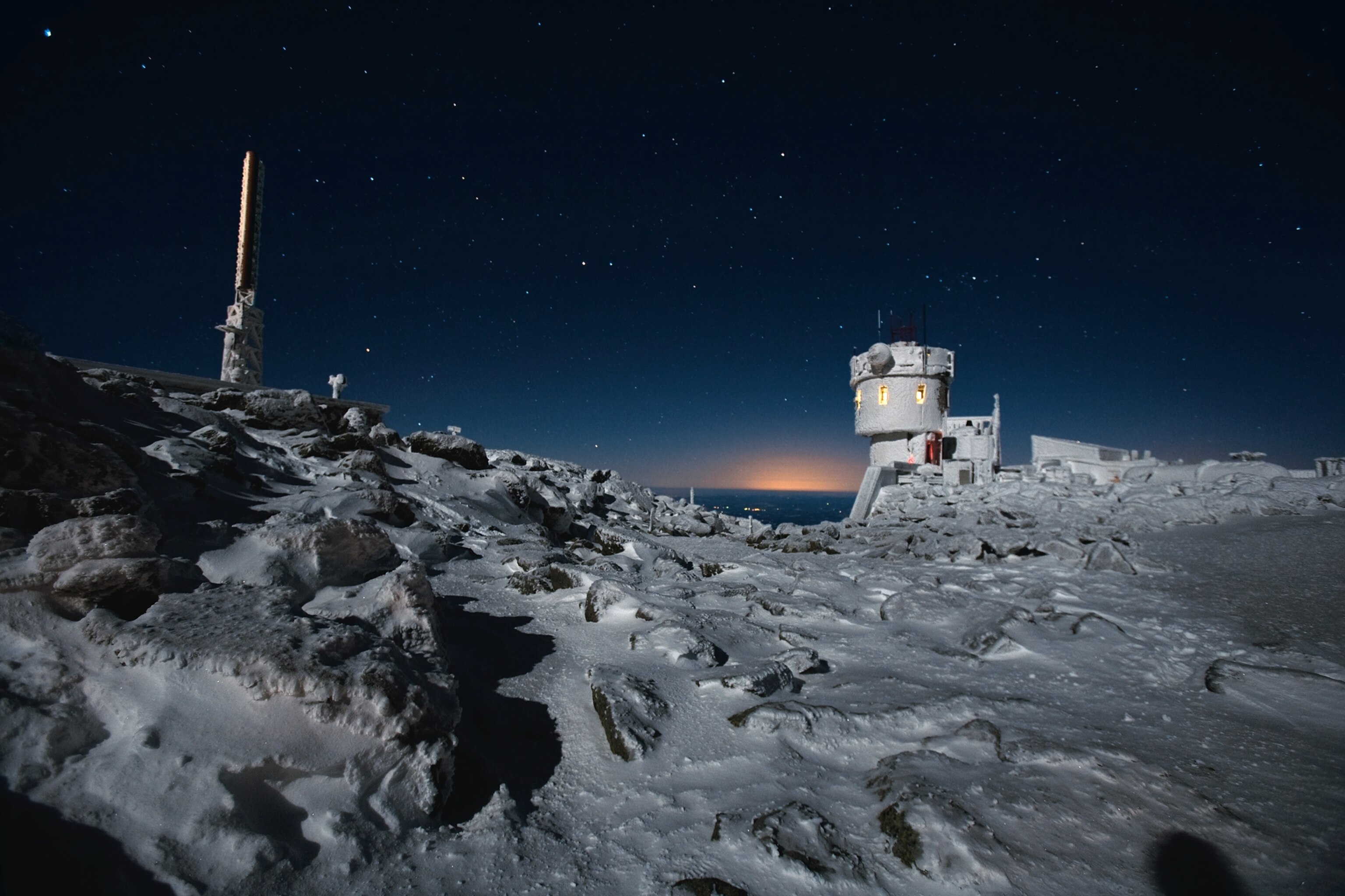 the glow of observatory lights and distant towns on a January night at Mount Washington