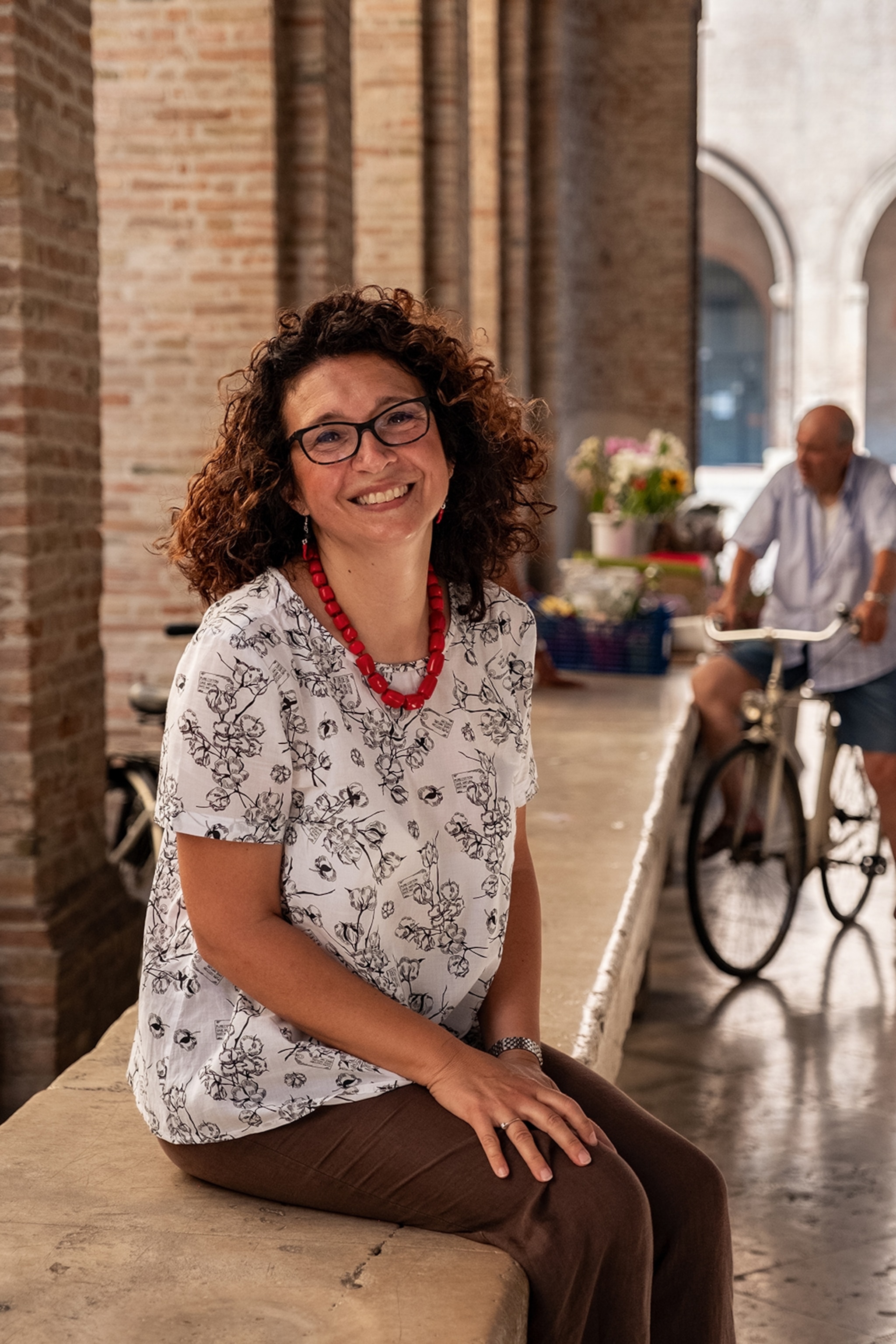 Woman sat on a stone wall smiling at the camera