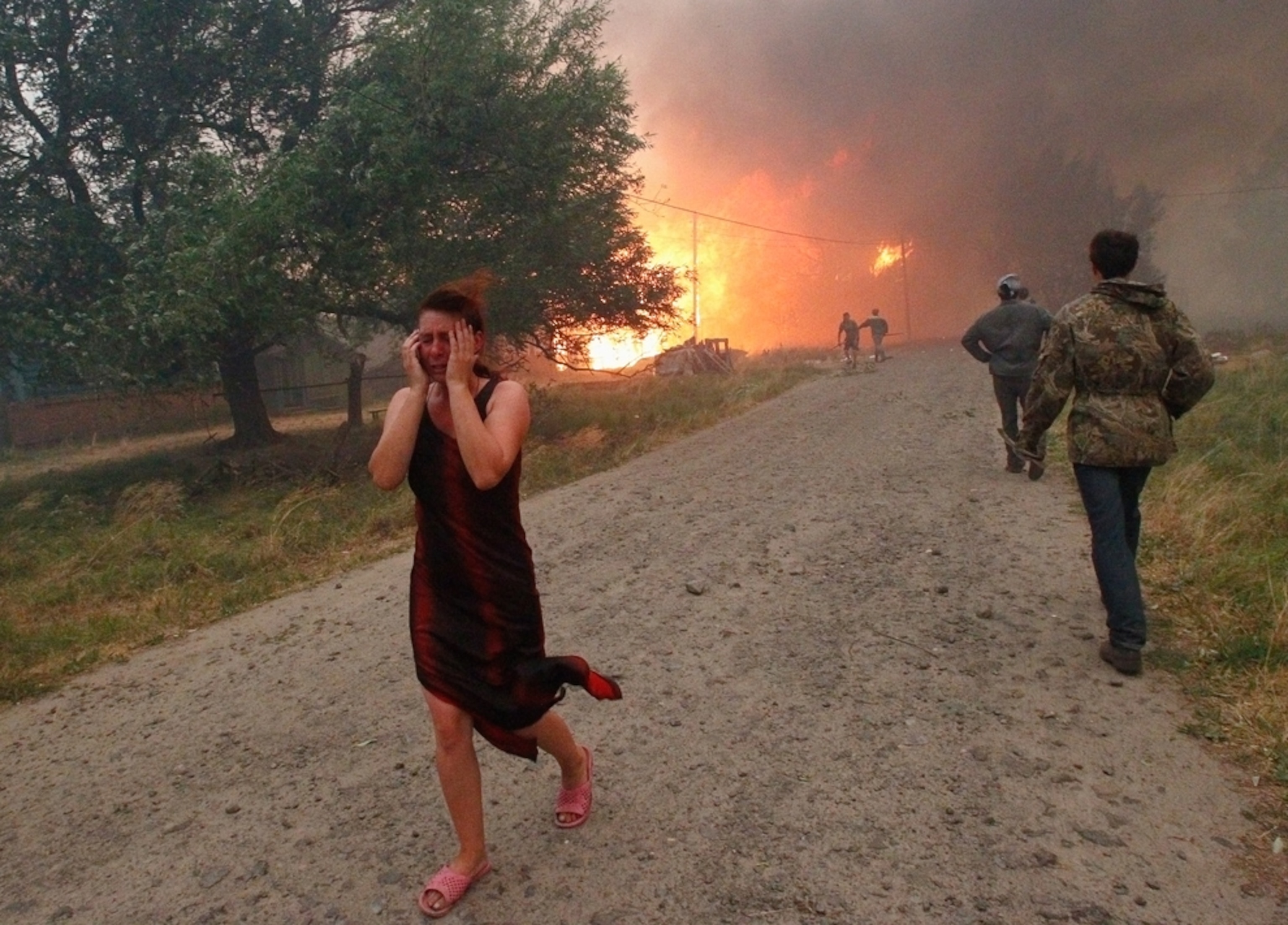 Picture of a woman walking from a forest fire in Russia, where a record heat wave has sparked hundreds of wildfires.