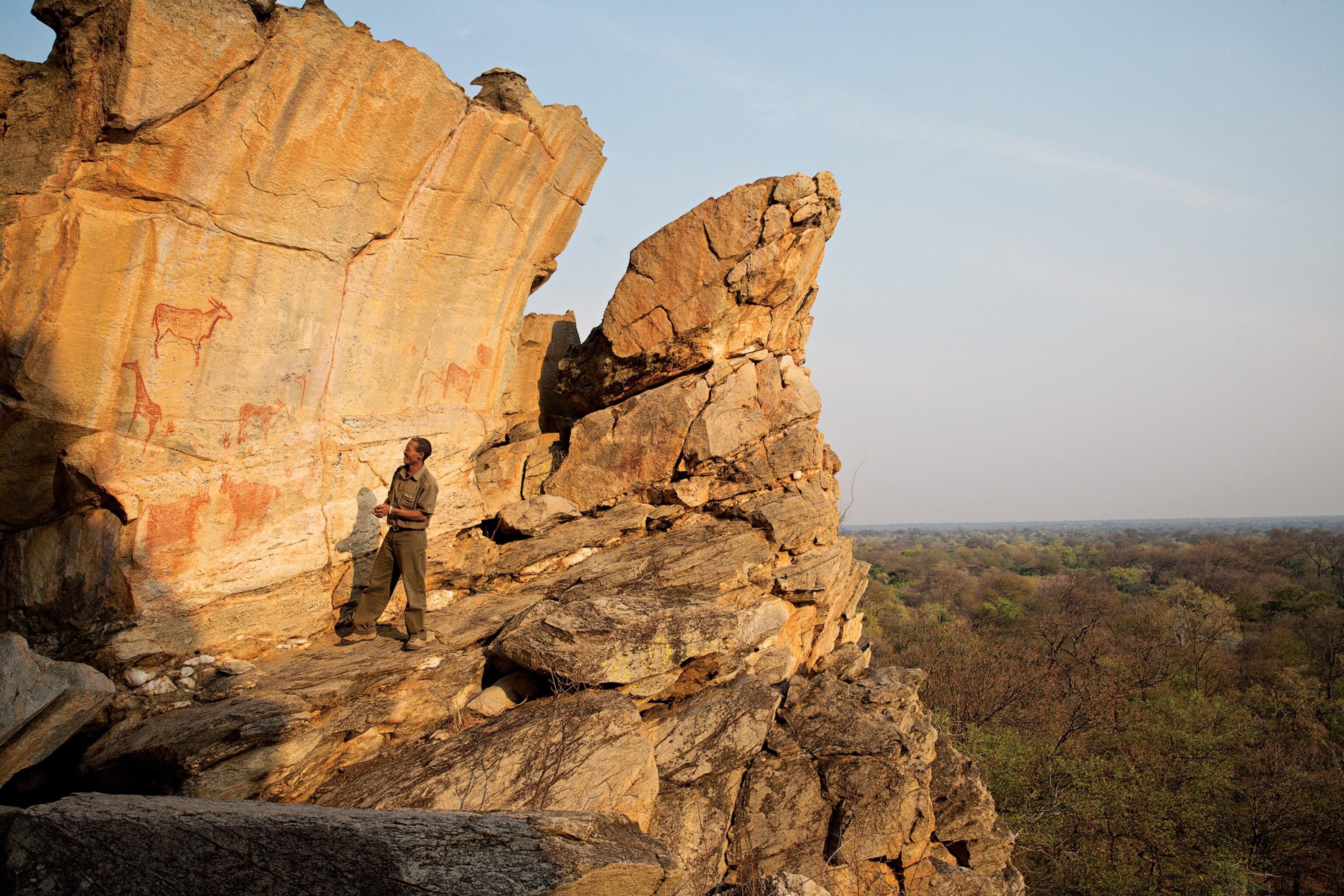 A bushman guide visits ancient cliff-side rock art at Tsodilo Hills