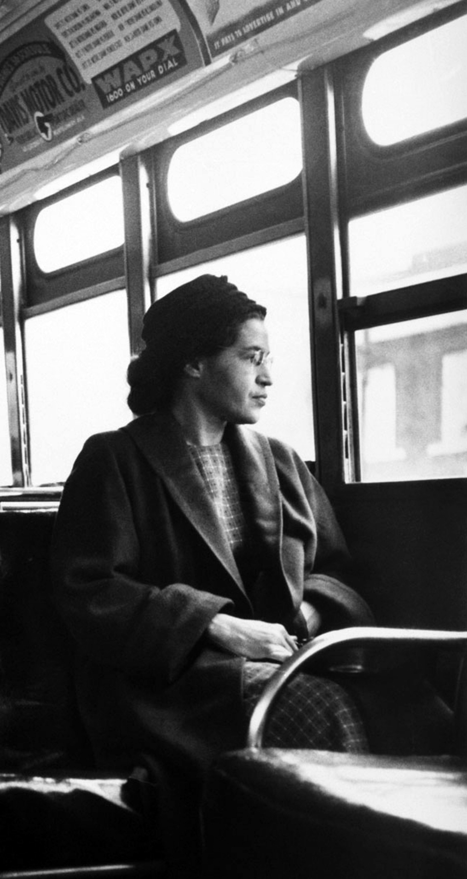 Rosa Parks seated at the front of a bus, looking out the window