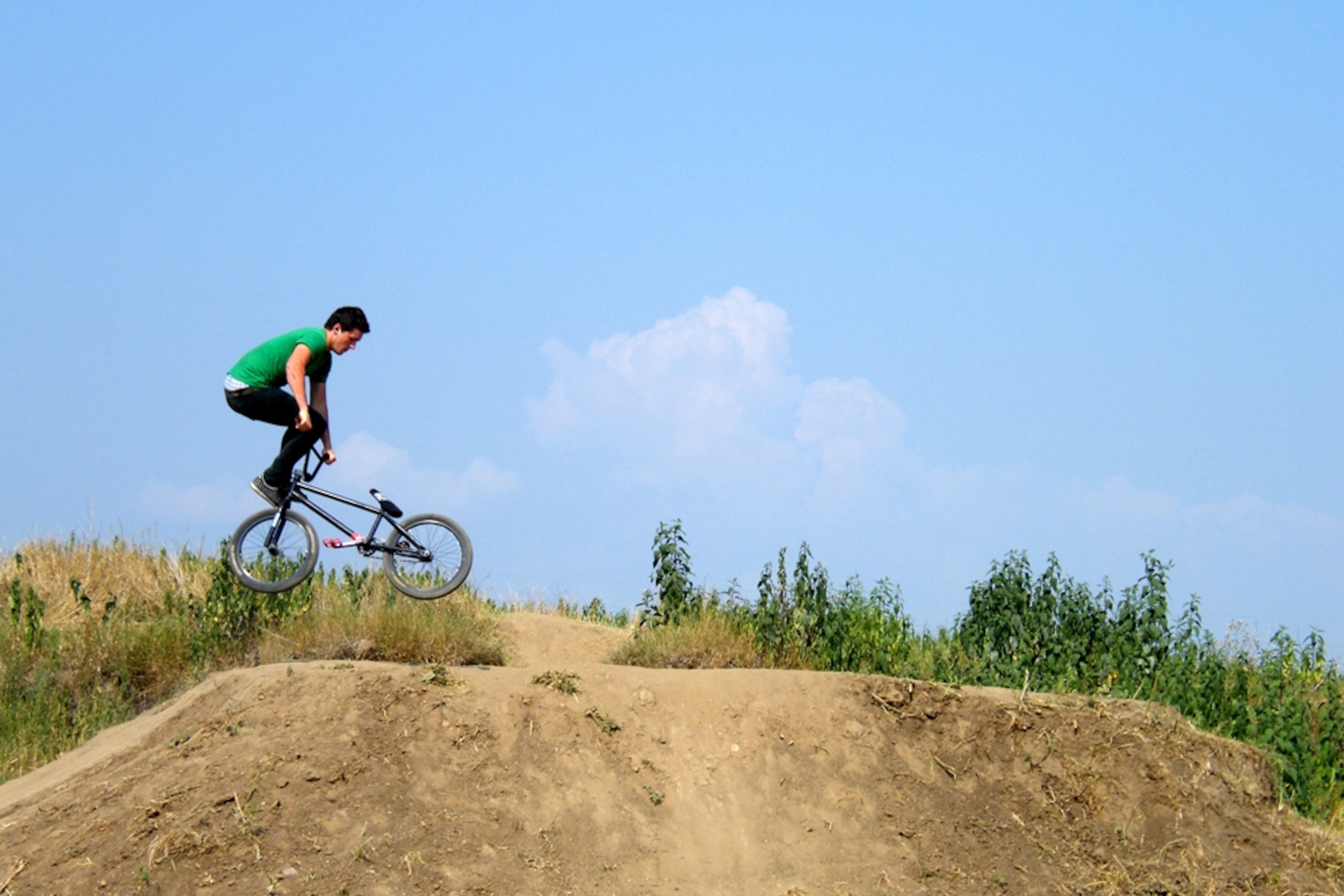 Rider jumping over hill on dirt track.