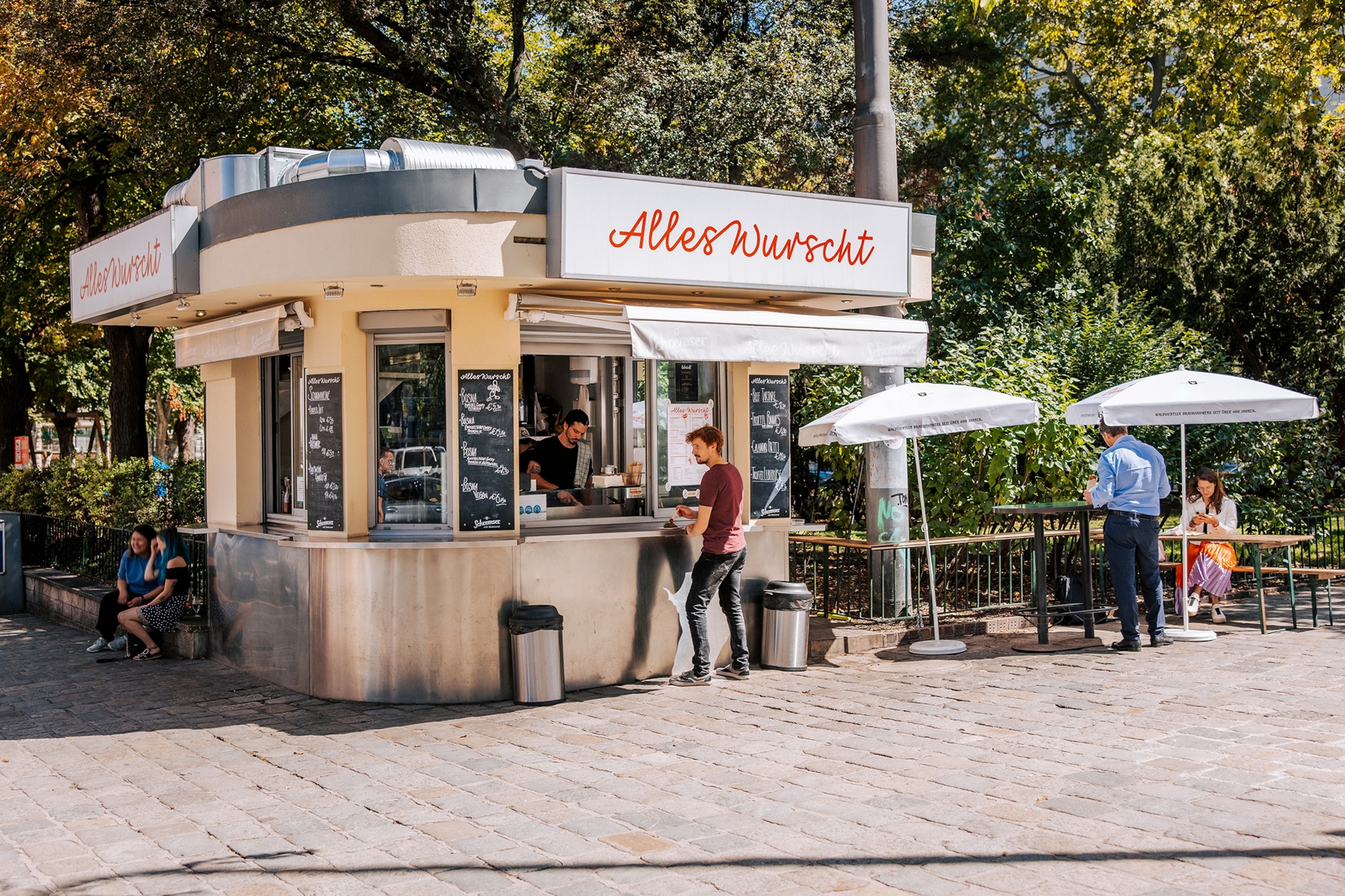 A street-side kiosk with tables outside and a retro design.