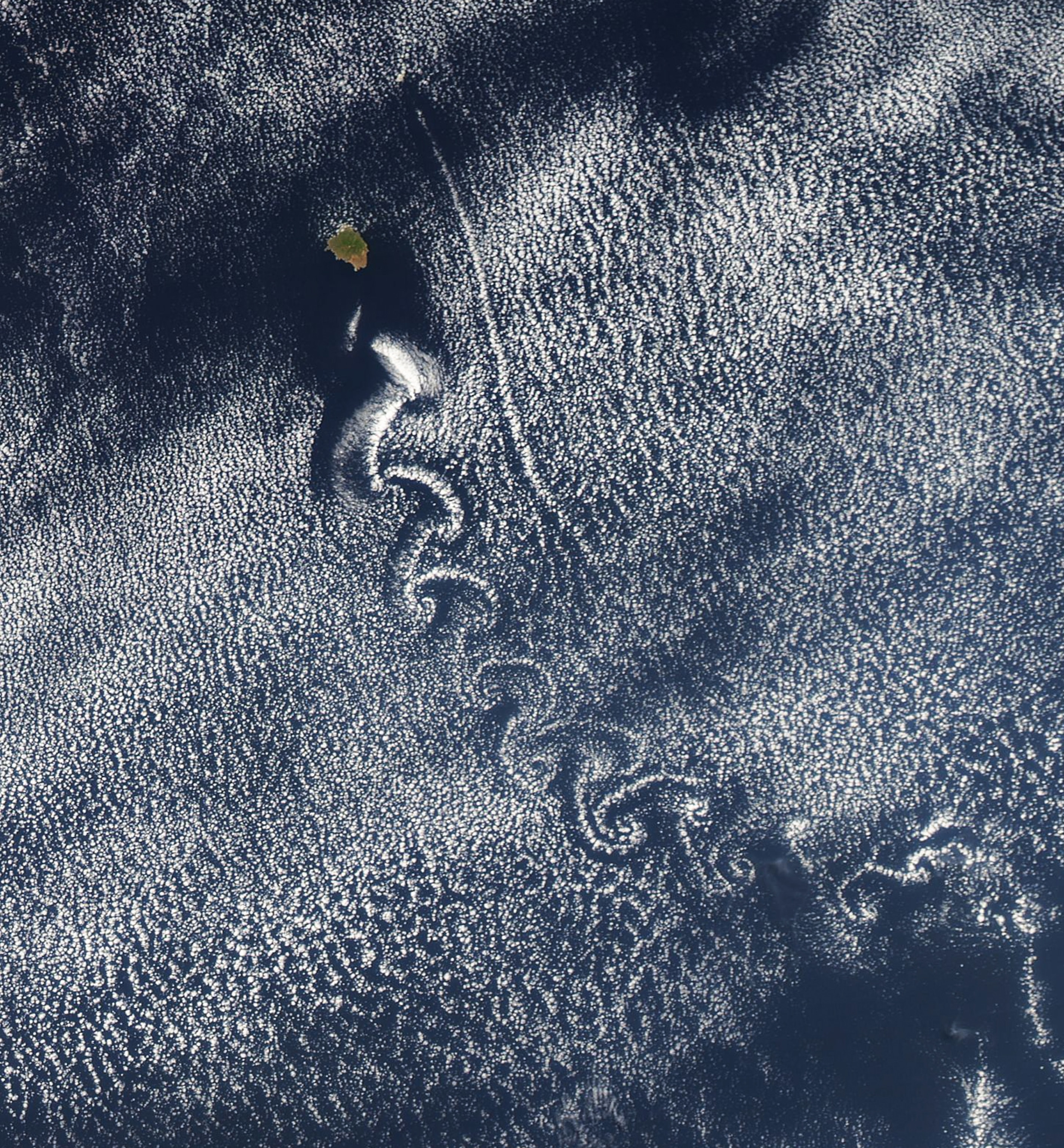 clouds swirling away from a volcanic island off the coast of Mexico