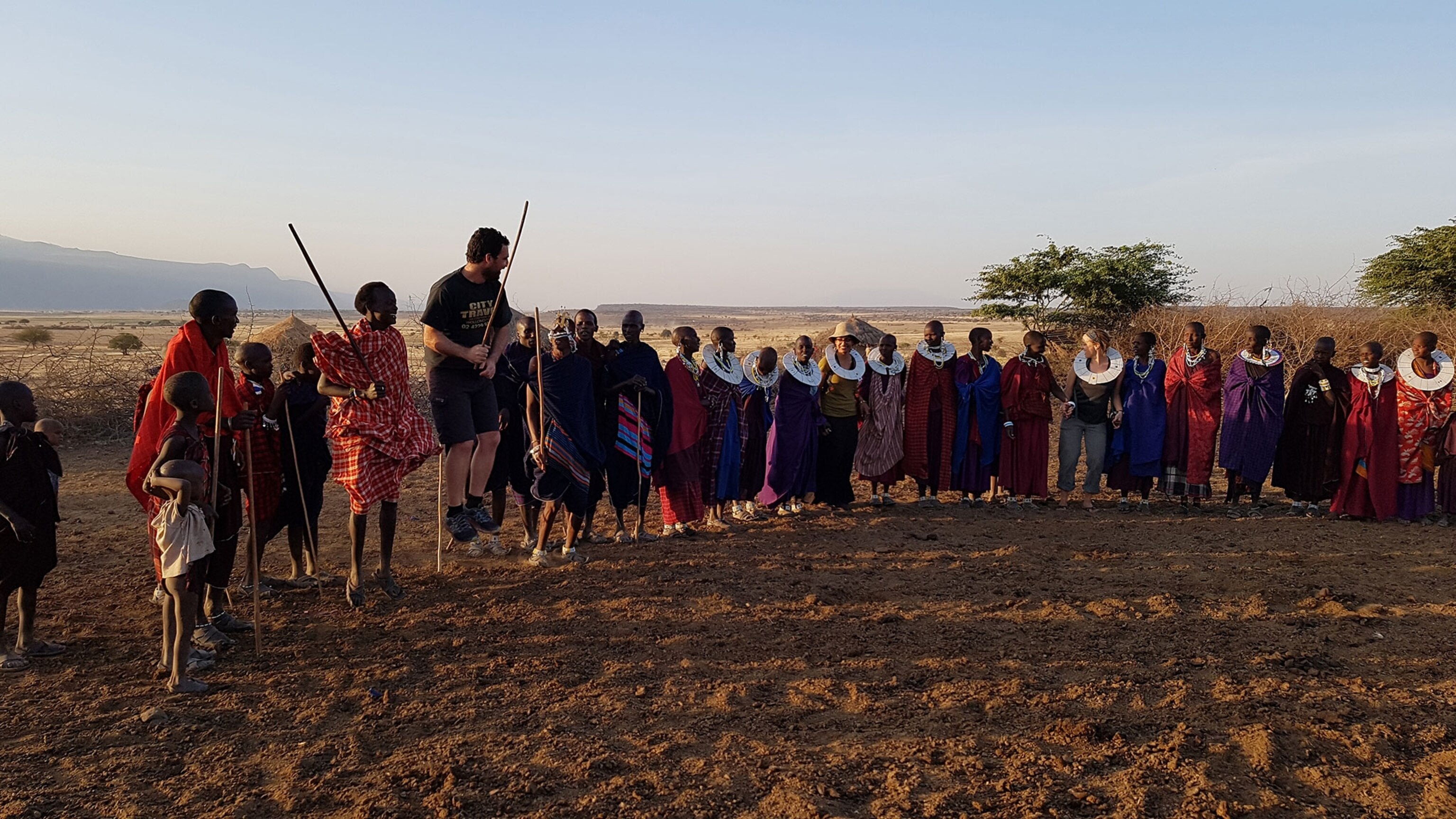 Maasai tribe participating in a traditional dance with bike tourists