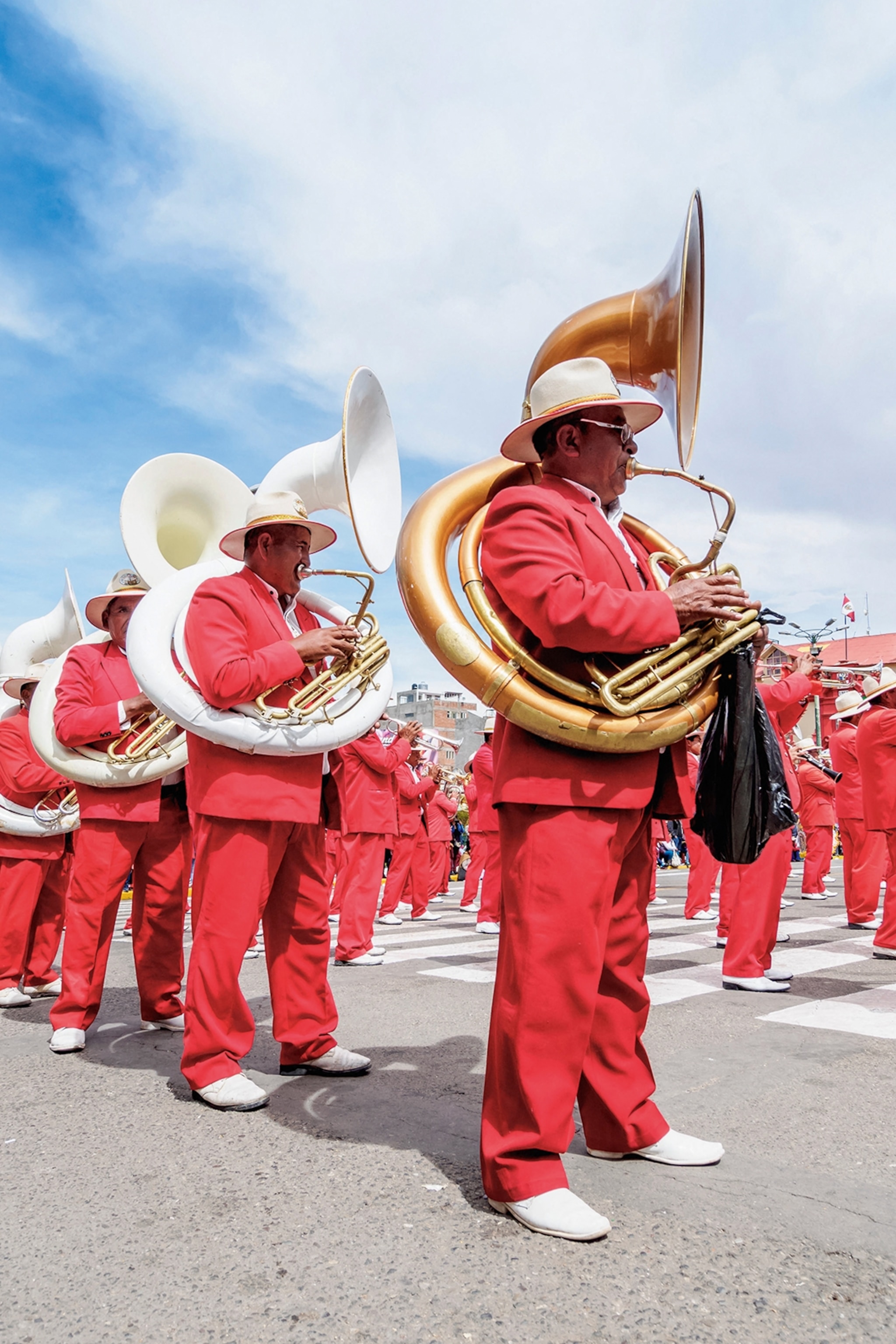 People in red play brass instruments in a town square