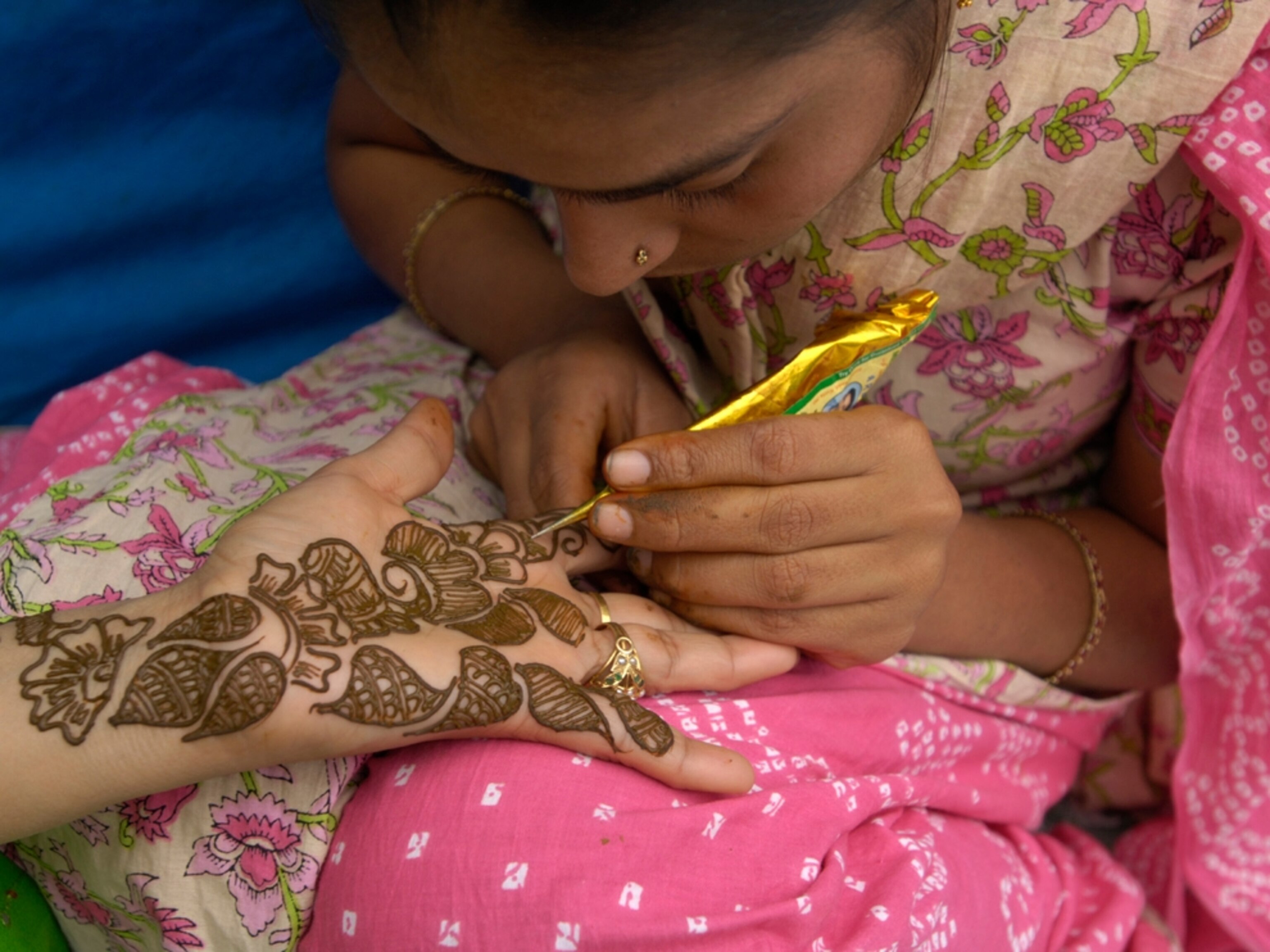 Woman paints with henna paste on hand, India