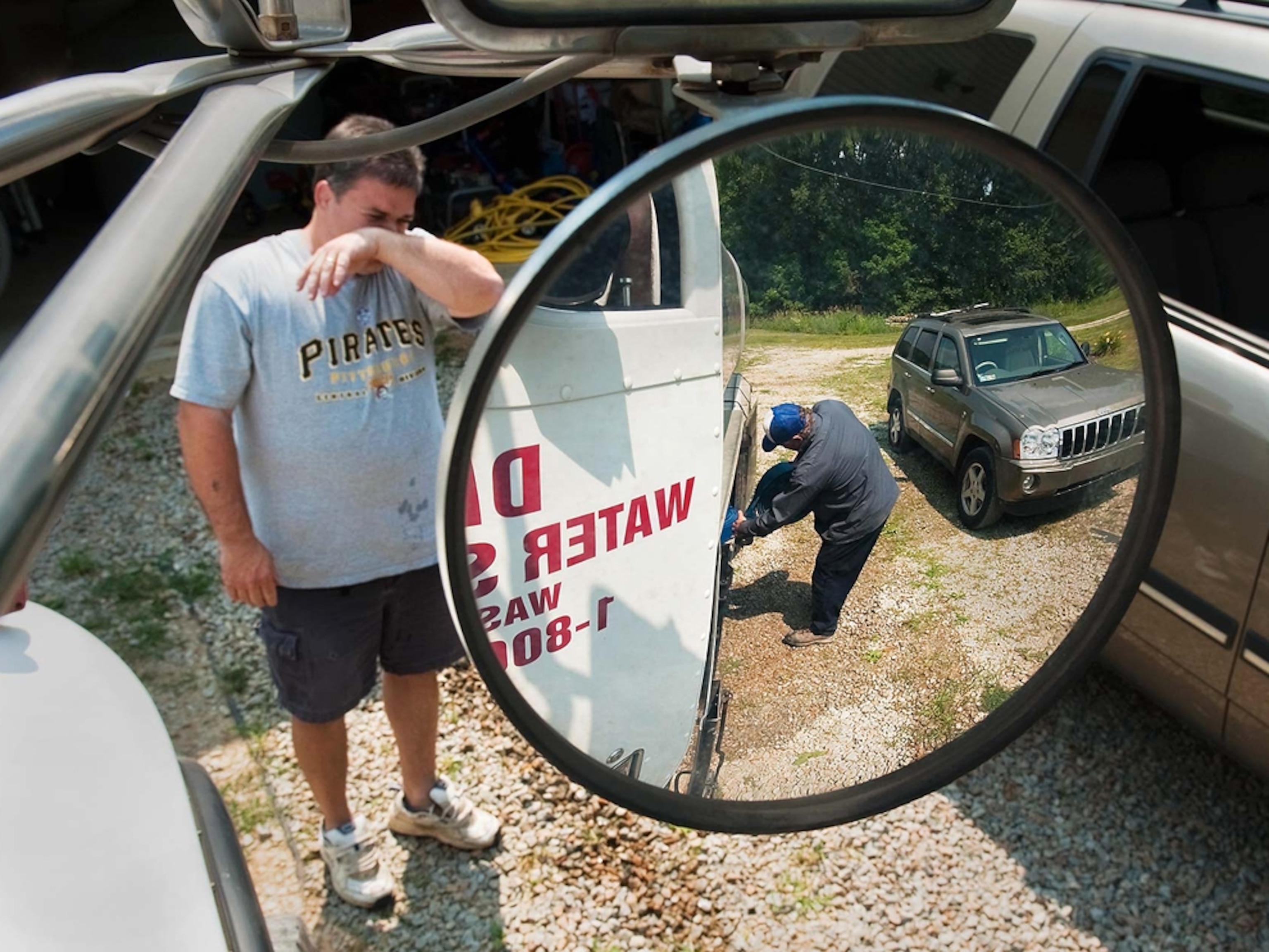 Chris Hallowich stands near a truck as water is delivered to his home.