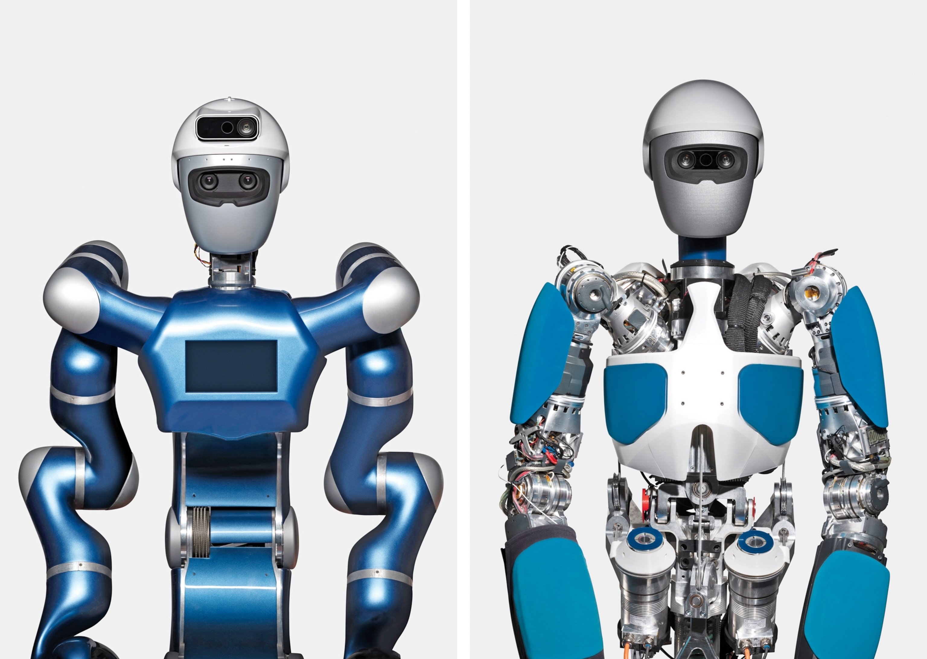Humanoid robots. On the left, a blue and silver humanoid robot with a screen on its chest, dual cameras on its head, and flexible arms. On the right, A humanoid robot with a metallic face, black eyes, and blue-armored limbs stands against a plain white background.