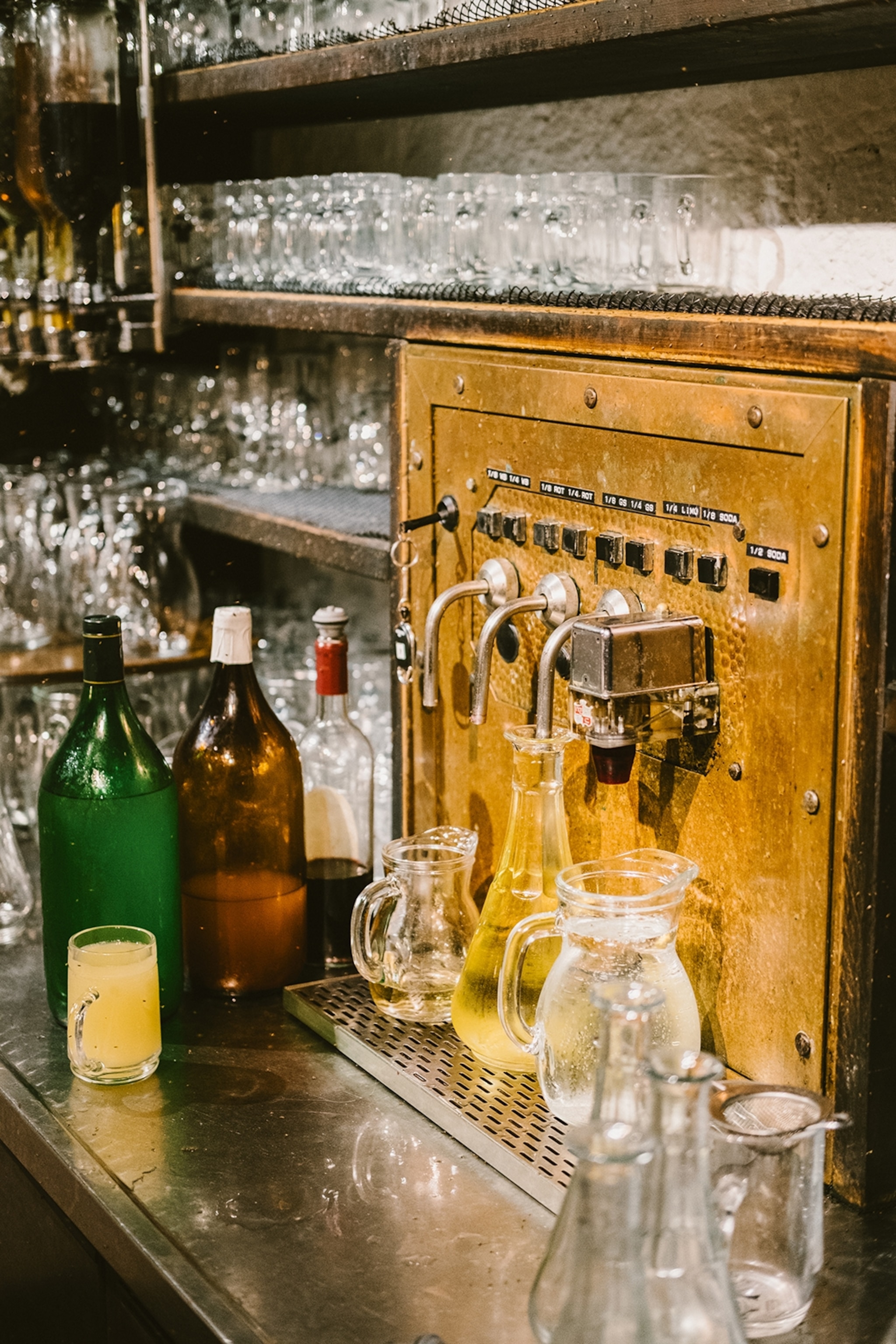 A wine tap with rows of glasses on shelving behind at a traditional bar.