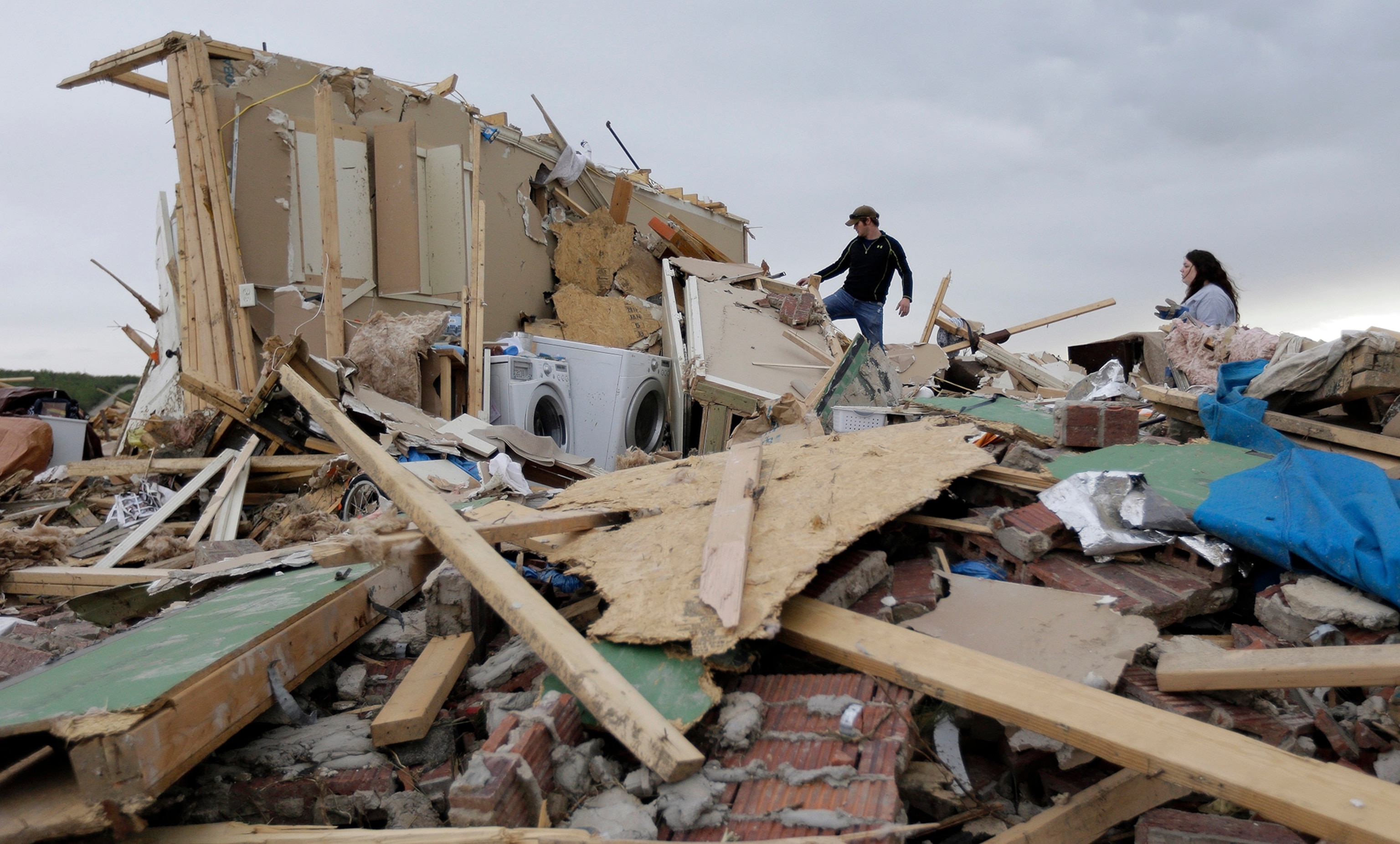 Austin Hargrove, left, and Haley Hracke, right, help recover personal items from a friends home that was destroyed by Sunday's tornado, Tuesday, April 29, 2014, in Vilonia, Ark. A dangerous storm system that spawned a chain of deadly tornadoes over three days flattened homes and businesses, forced frightened residents in more than half a dozen states to take cover and left tens of thousands in the dark Tuesday morning. (AP Photo/Eric Gay)