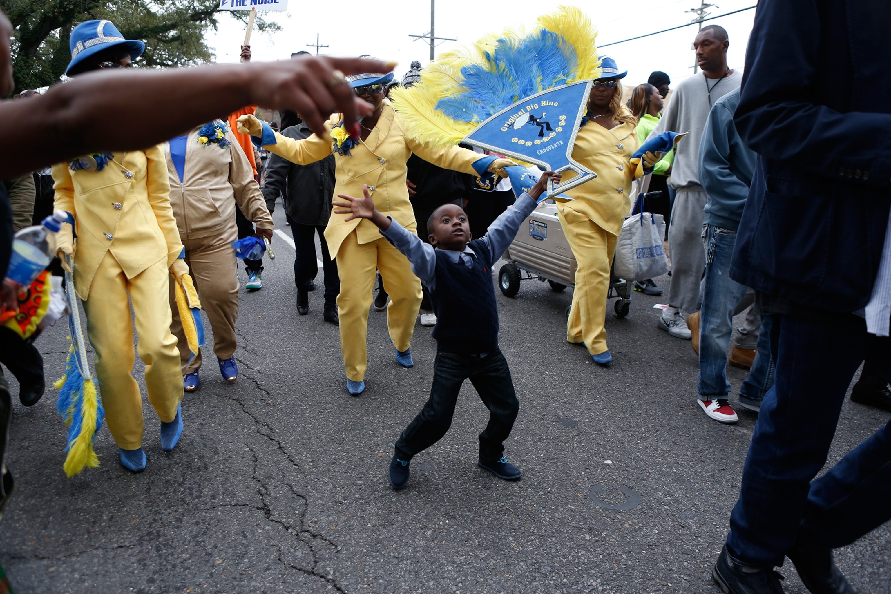 a young man hoisting one of the decorative hand fans and dances as the parade nears the end of the route on St. Claude Avenue in New Orleans.