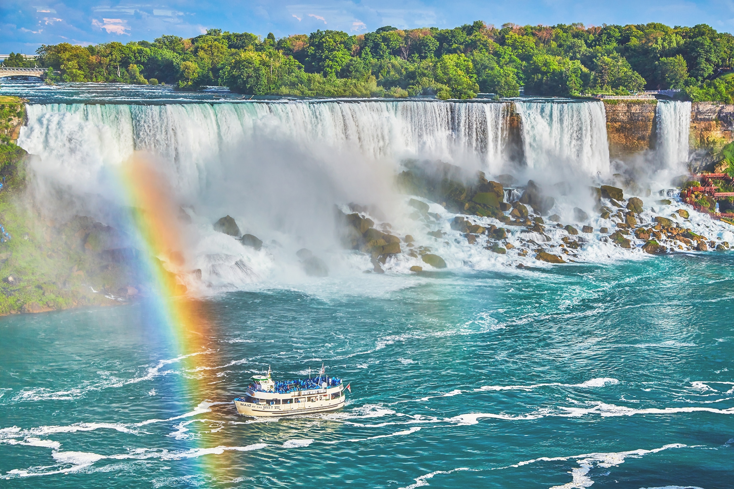 Rainbow at American Falls with tourist boats.