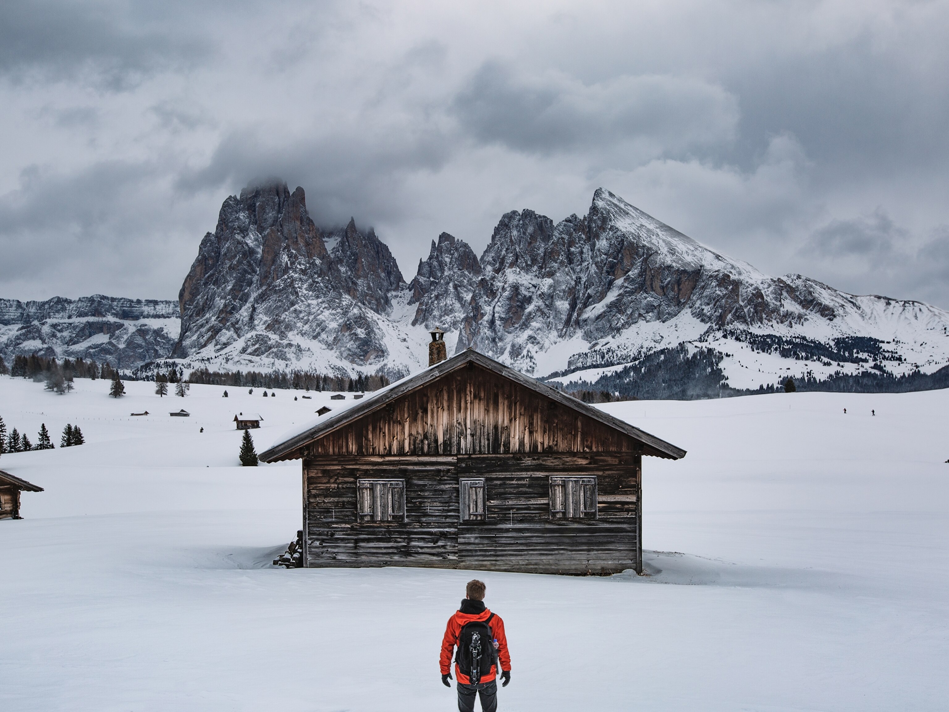 a man standing in front of a snow covered cabin in the Dolomites of Italy