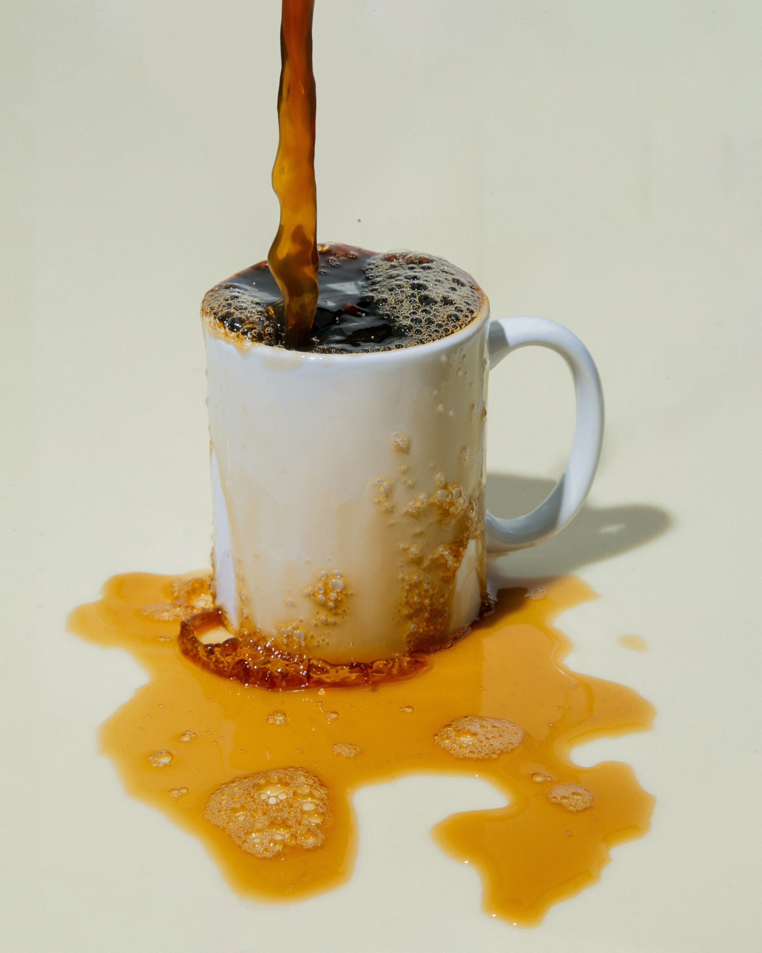 Coffee pouring into an overflowing white mug