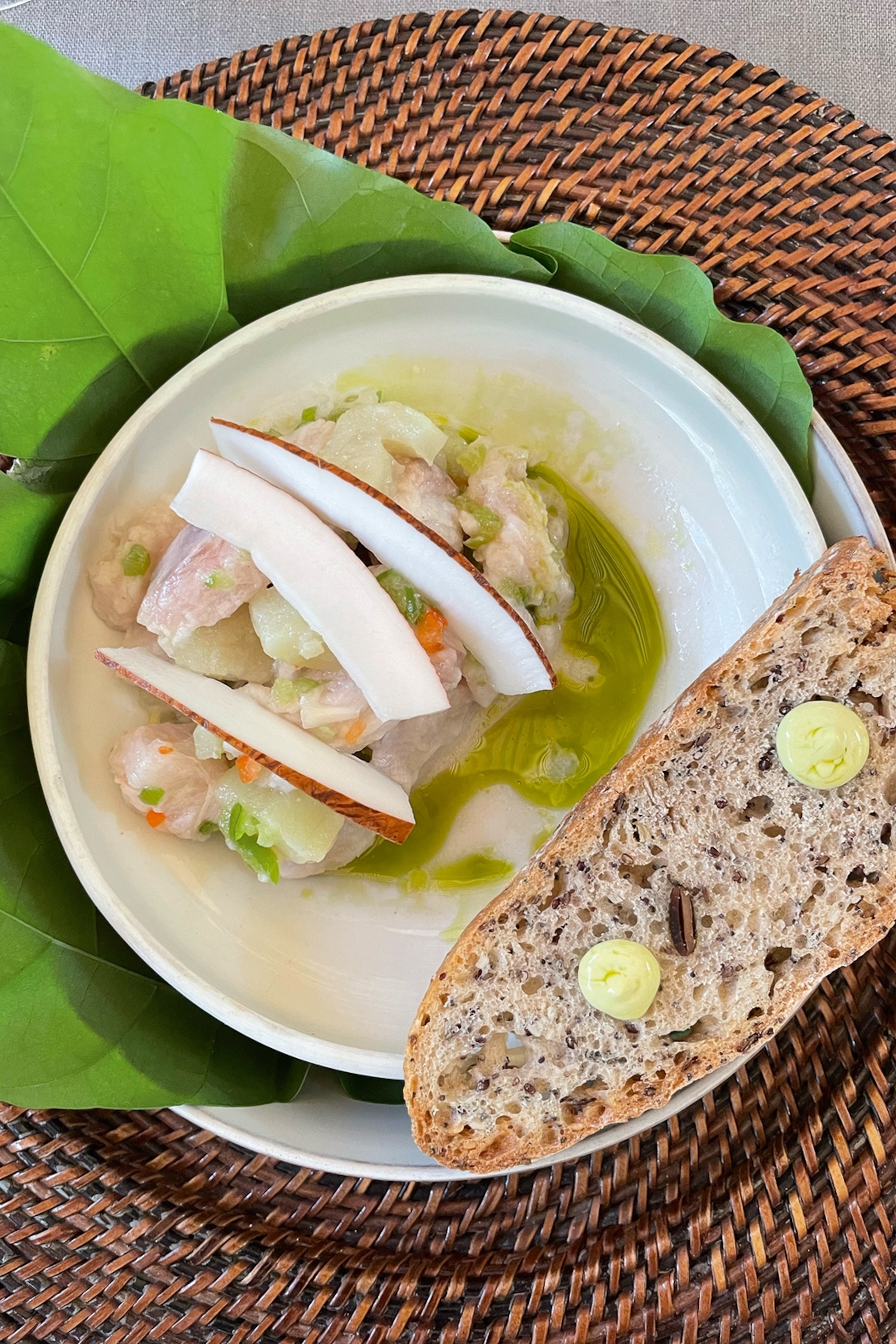 A plate of raw, seasoned fish served with onion and a slice of bread.