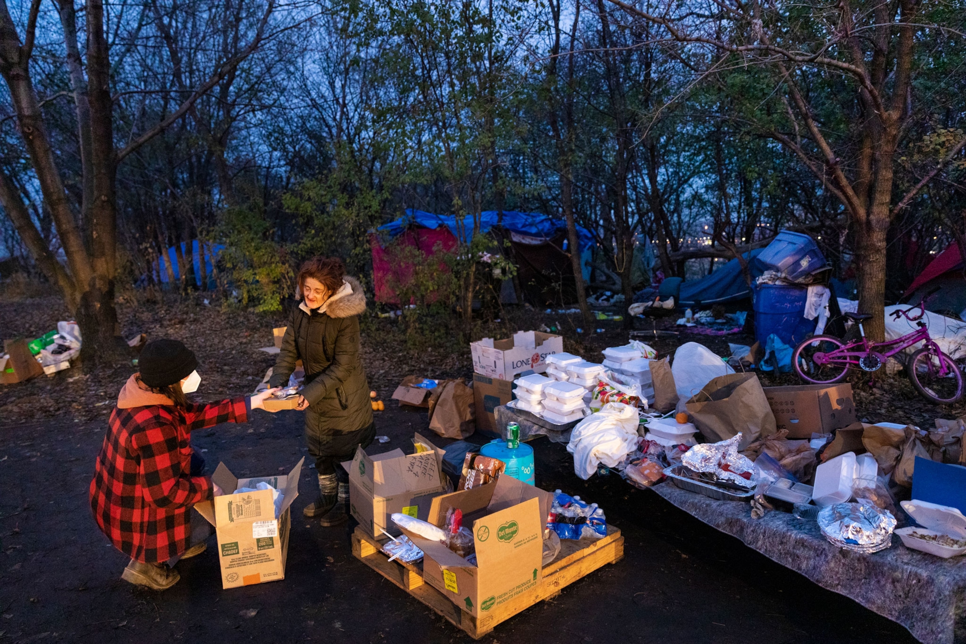 Homeless woman accepts donated food from volunteer.