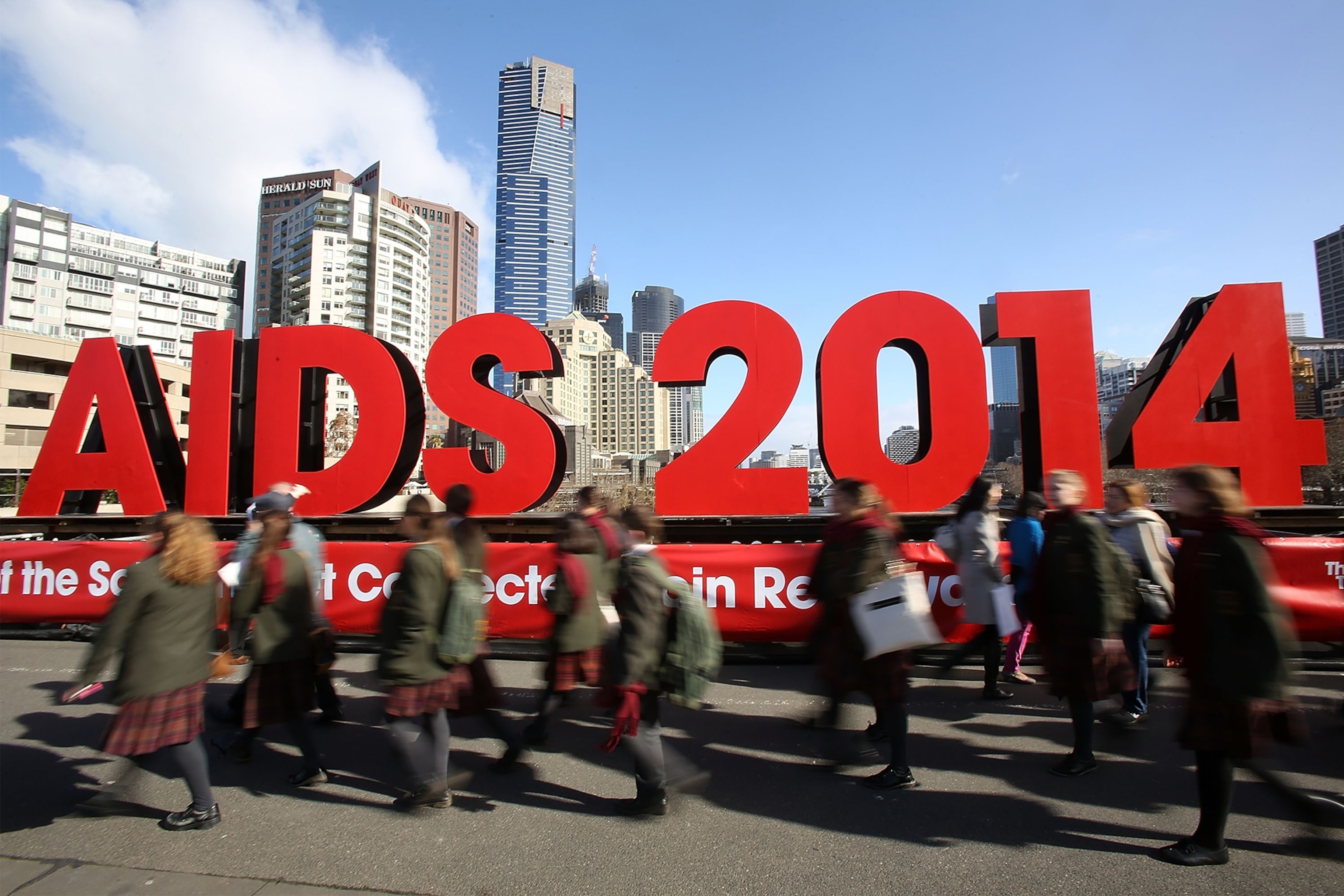Members of the public walk past signage on the Princes Bridge for the 20th International AIDS Conference on July 18, 2014 in Melbourne, Australia.