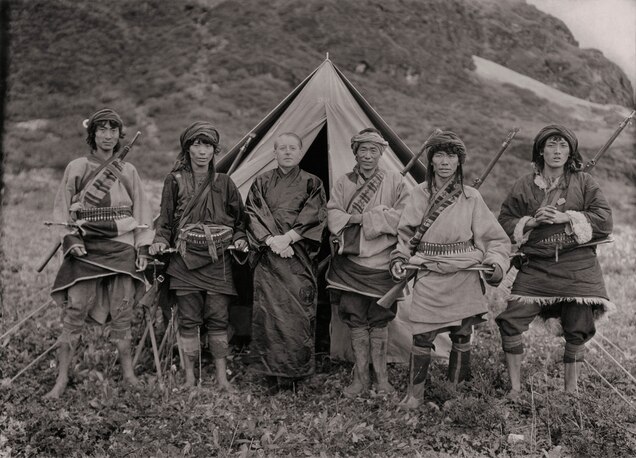 Black and white photo of Joseph Rock surrounded by Chinese men