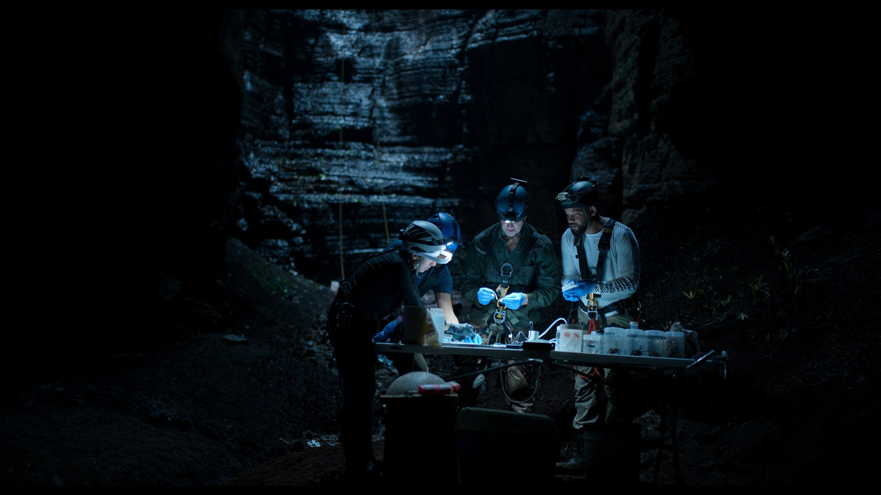 A group of people in a cave stand around a table.