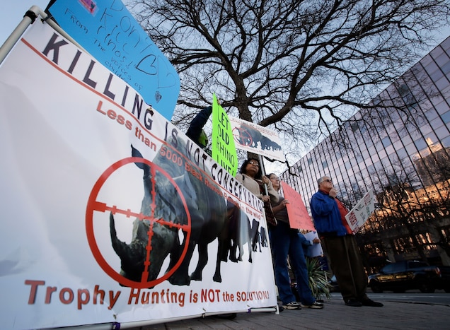 Hunting rhinos saves rhinos, say members of the Dallas Safari Club, whose opponents hold signs at a club event in January 2014. The World Bank has approved money for sport hunting of elephants and lions in Mozambique, where the practice has long been favored as a way to preserve wildlife. Photograph by Tony Gutierrez, AP